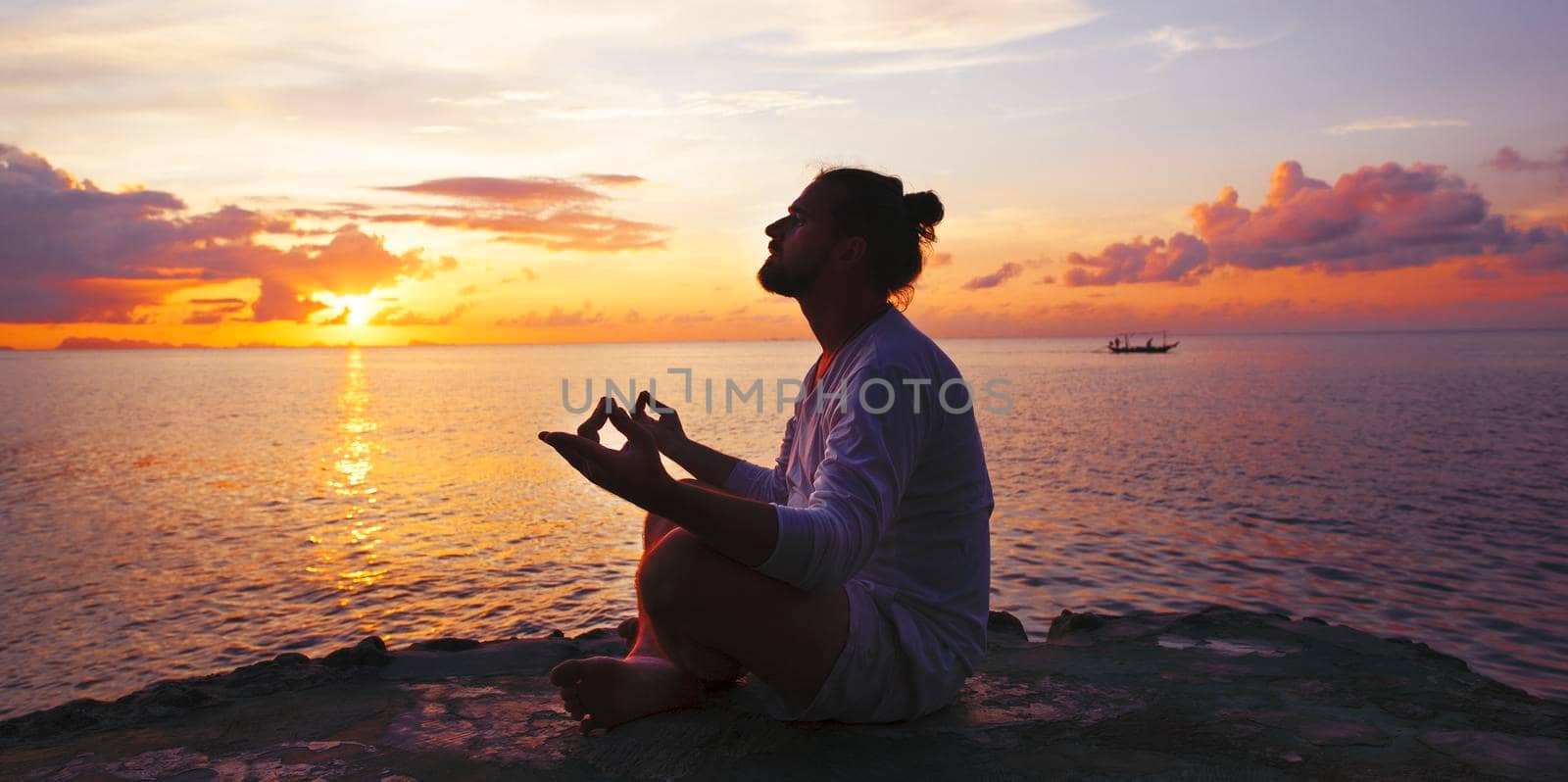 Yoga scene man silhouette in sunset background.