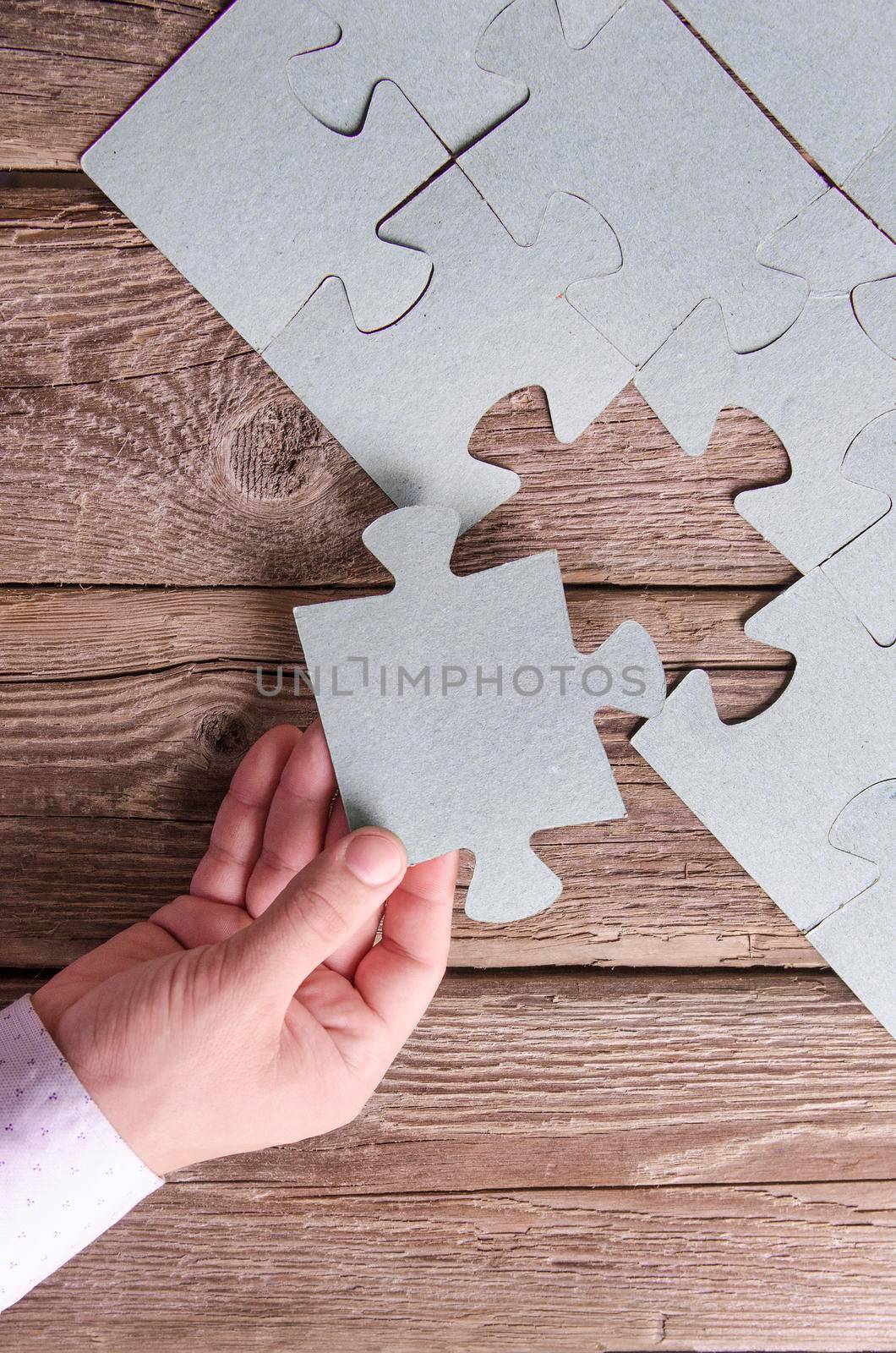 Incomplete puzzles lying on wooden rustic boards. by Jyliana