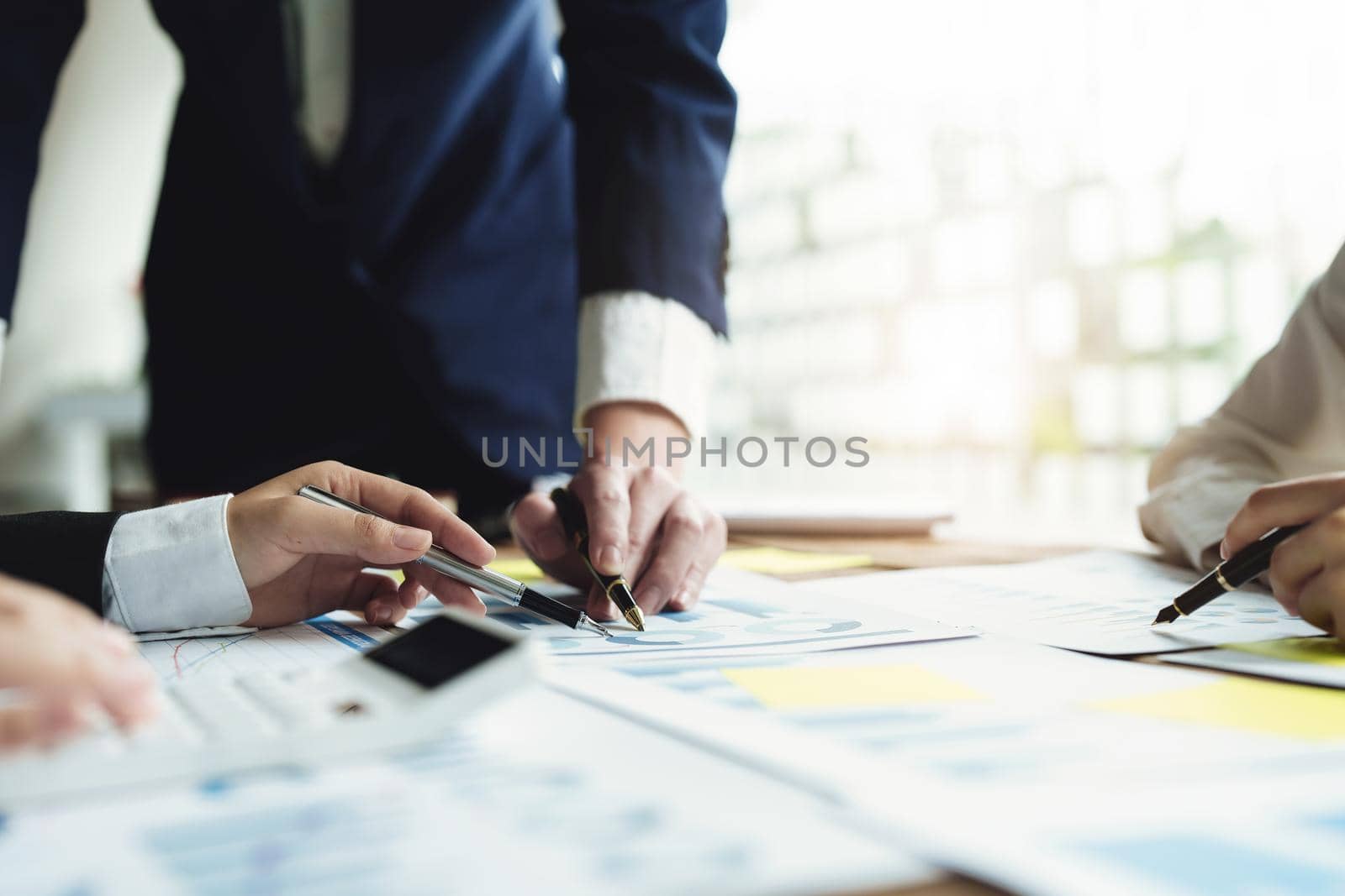 Male businessman pointing to take summarizing marketing strategy documents with female colleagues in meeting, teamwork, investment planning.
