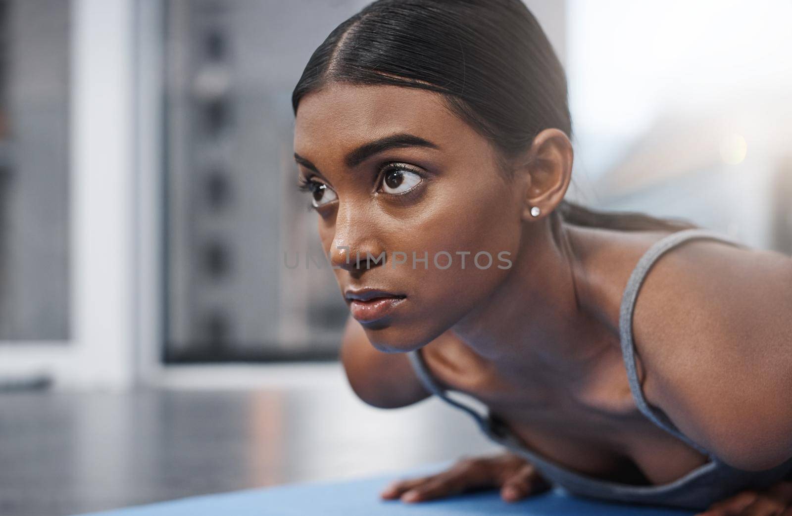 Winners never lose focus. Close up shot of an attractive young woman busy exercising on her gym mat at home. by YuriArcurs