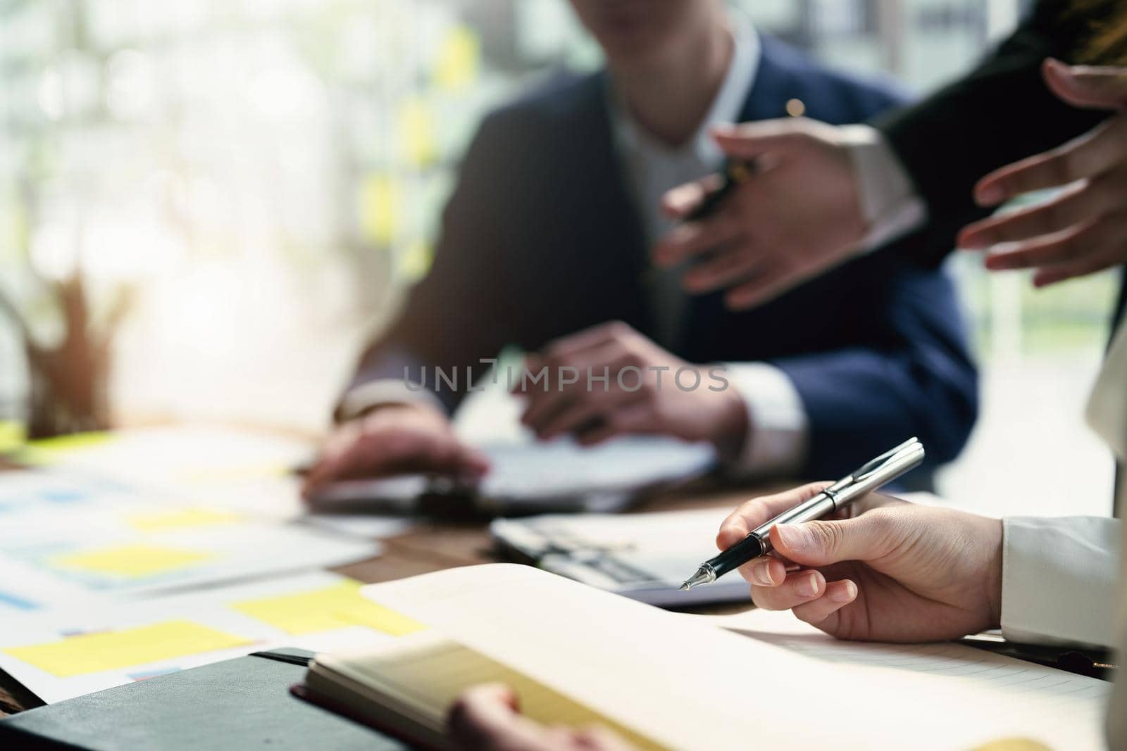 Male businessman pointing to take summarizing marketing strategy documents with female colleagues in meeting, teamwork, investment planning.