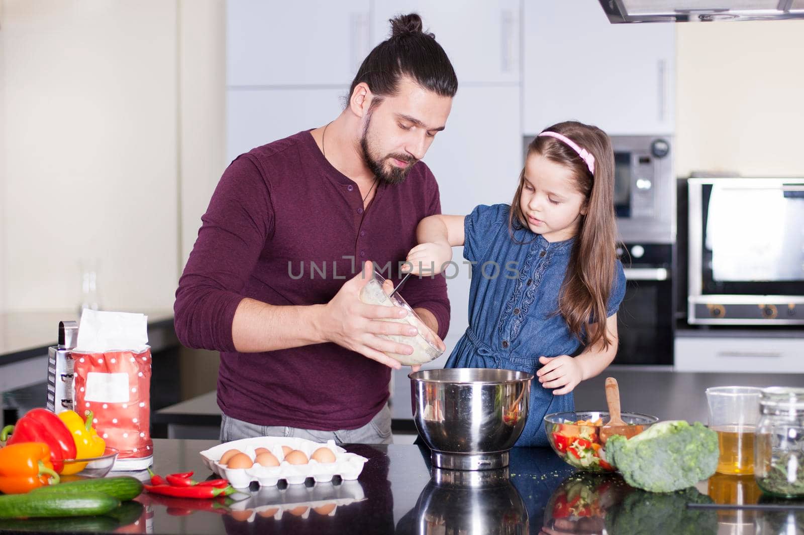 Father and happy daughter making meal together in kitchen. Cooking classes concept