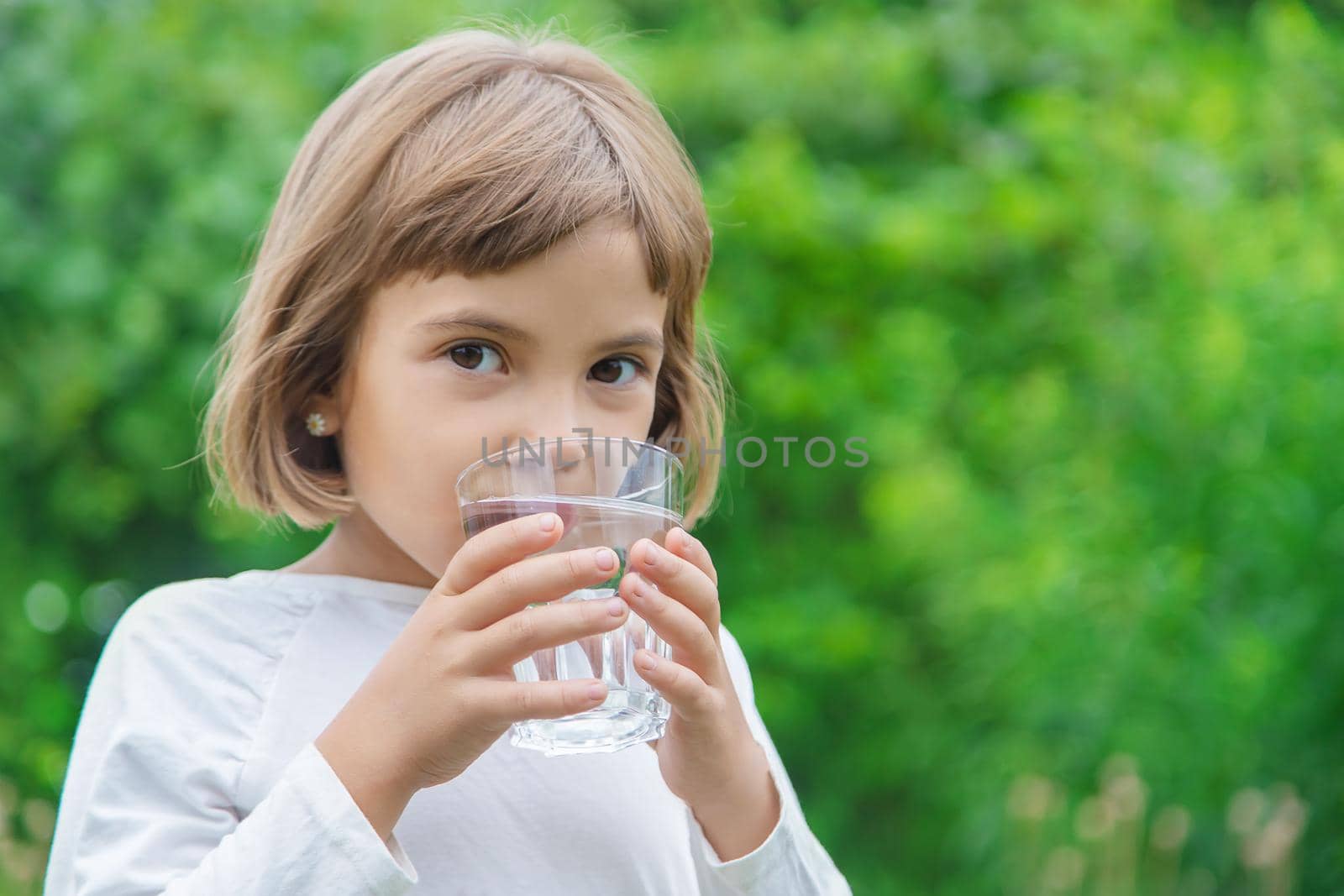 child drinks water from a glass. Selective focus. by yanadjana