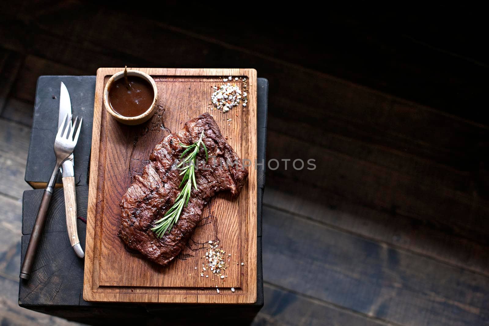 Beef steak. Piece of Grilled BBQ beef marinated in spices and herbs on a rustic wooden board over rough wooden desk with a copy space. Top view