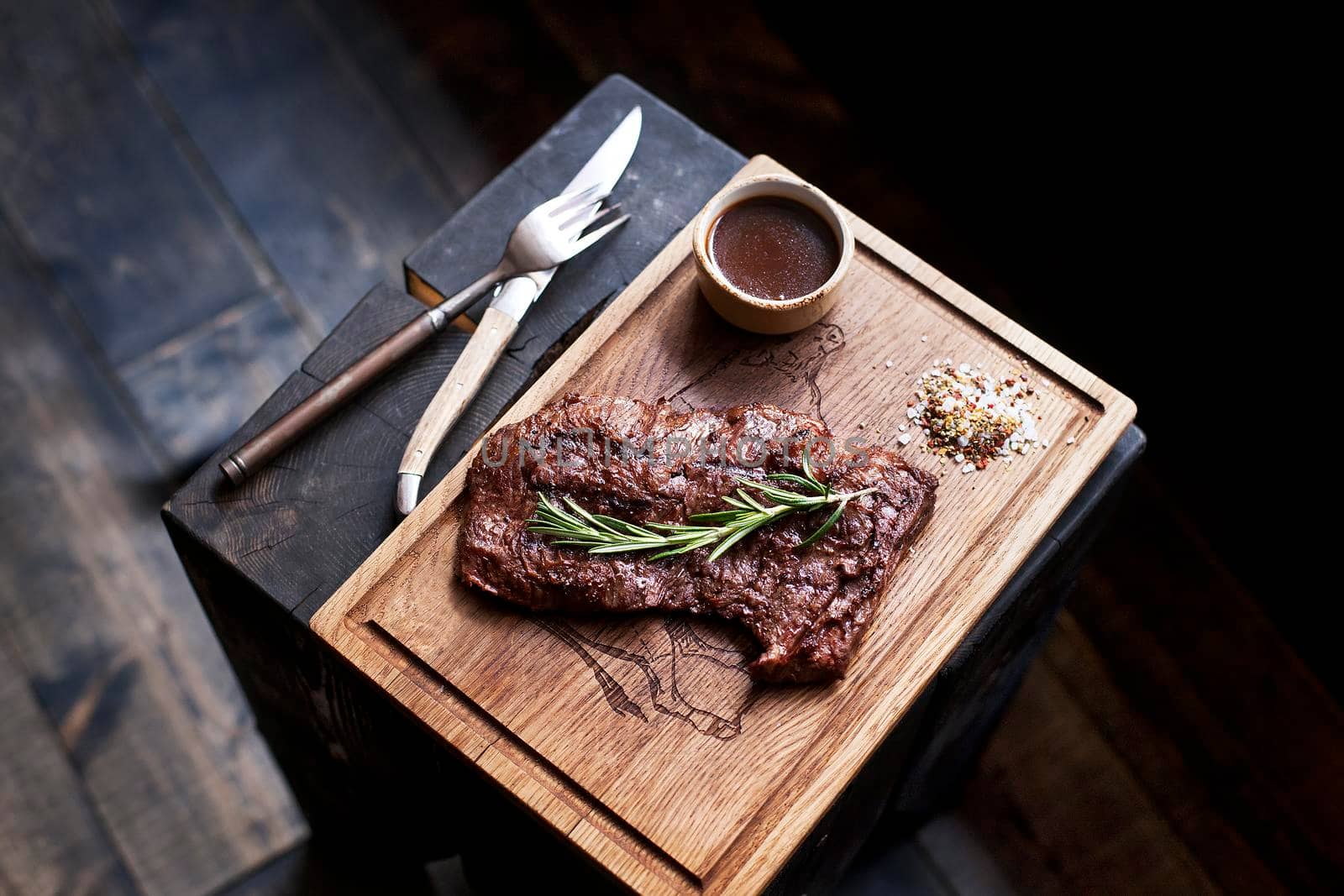 Beef steak. Piece of Grilled BBQ beef marinated in spices and herbs on a rustic wooden board over rough wooden desk with a copy space. Top view. Stock Image