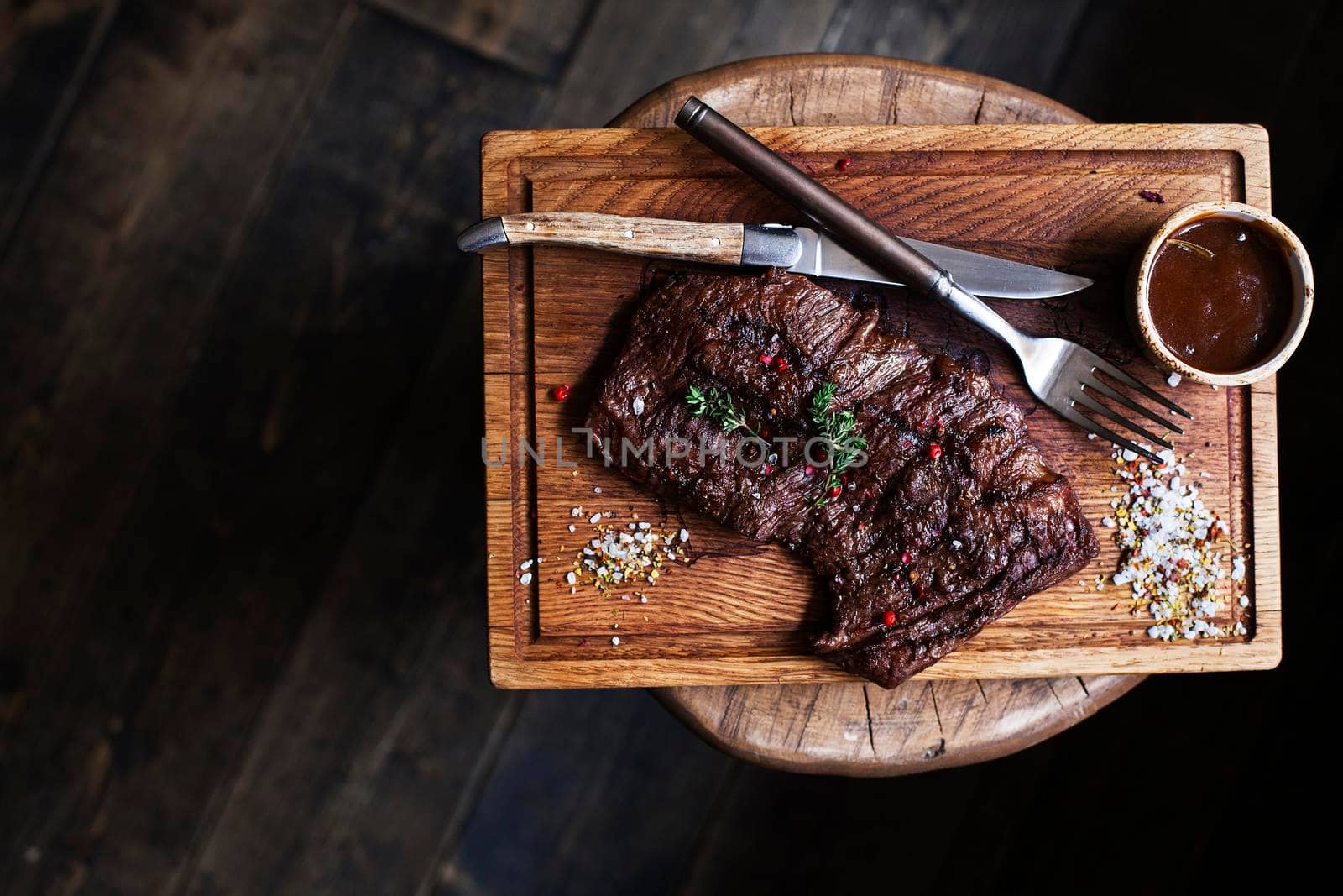 Beef steak. Piece of Grilled BBQ beef marinated in spices and herbs on a rustic wooden board over rough wooden desk with a copy space. Top view