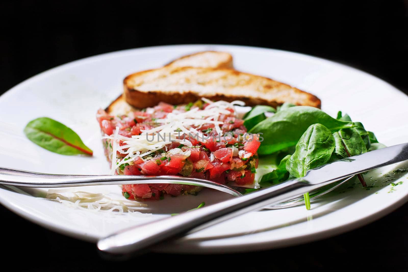 Tartare of beef with spinach on a white plate. Isolatrd on black.