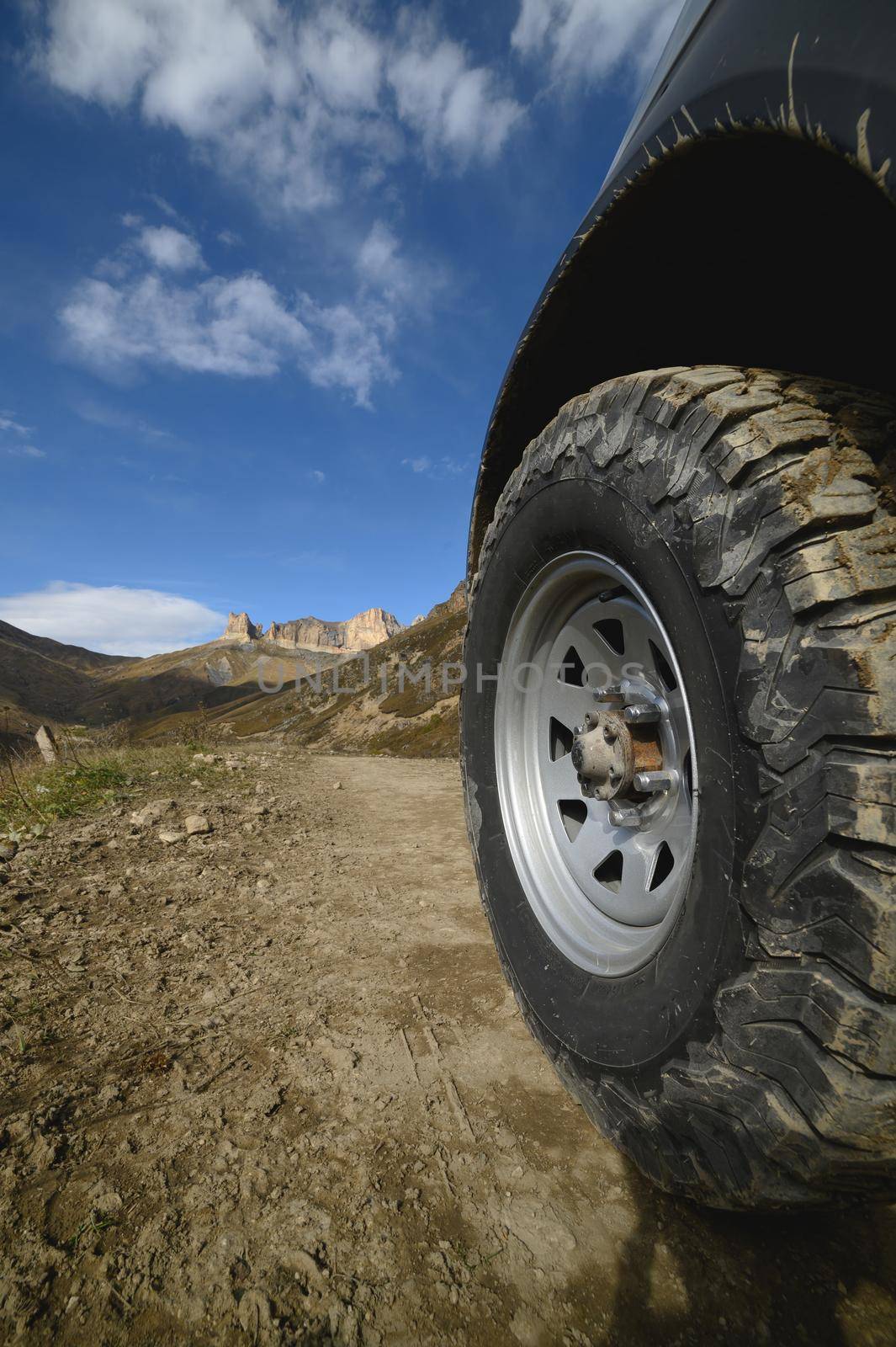 Big car wheel on mountains at day backdrop. Offroad 4x4 concept by yanik88