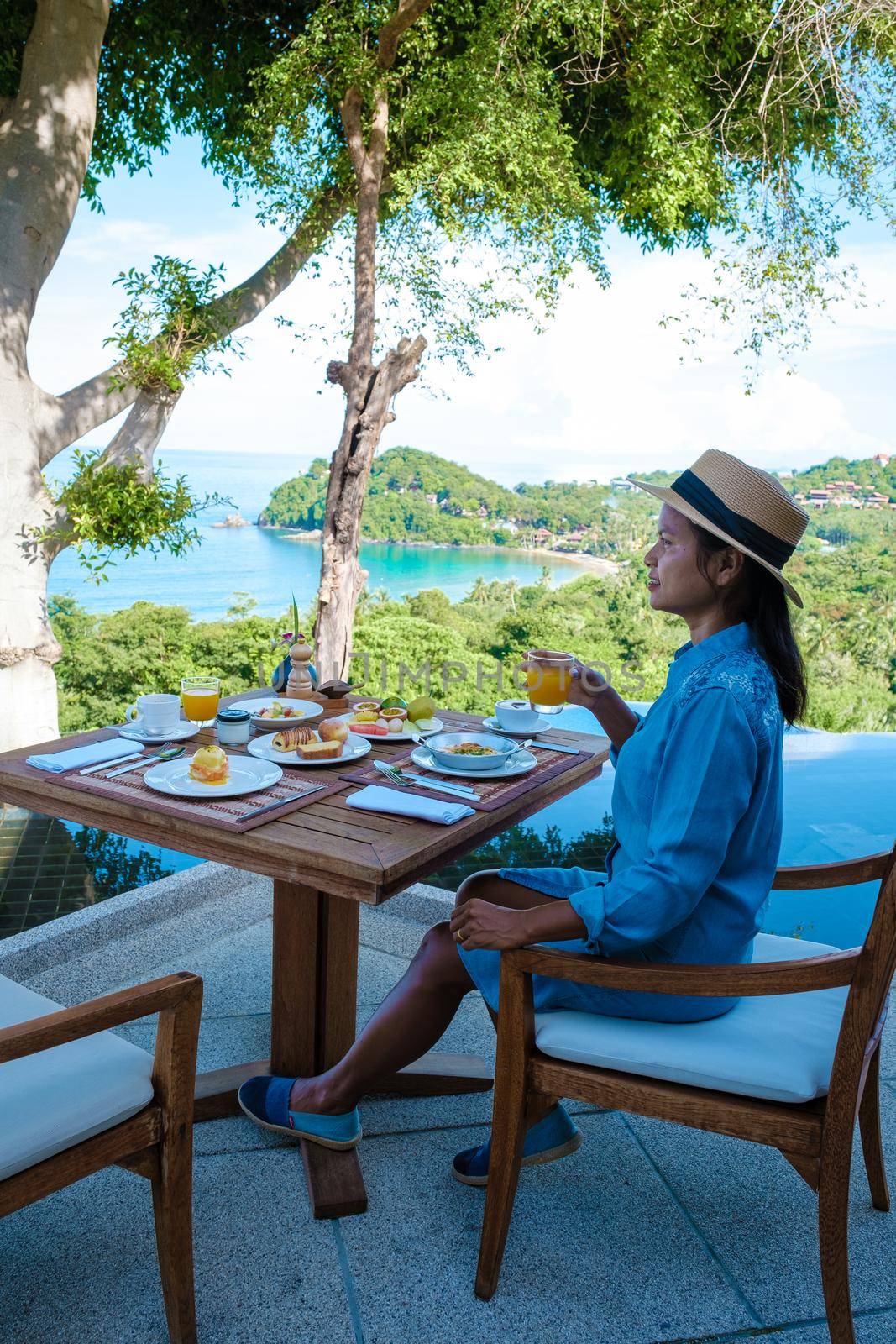 Luxury breakfast with a view at the pool and ocean in Thailand Koh Lanta, woman having breakfast in the morning outside