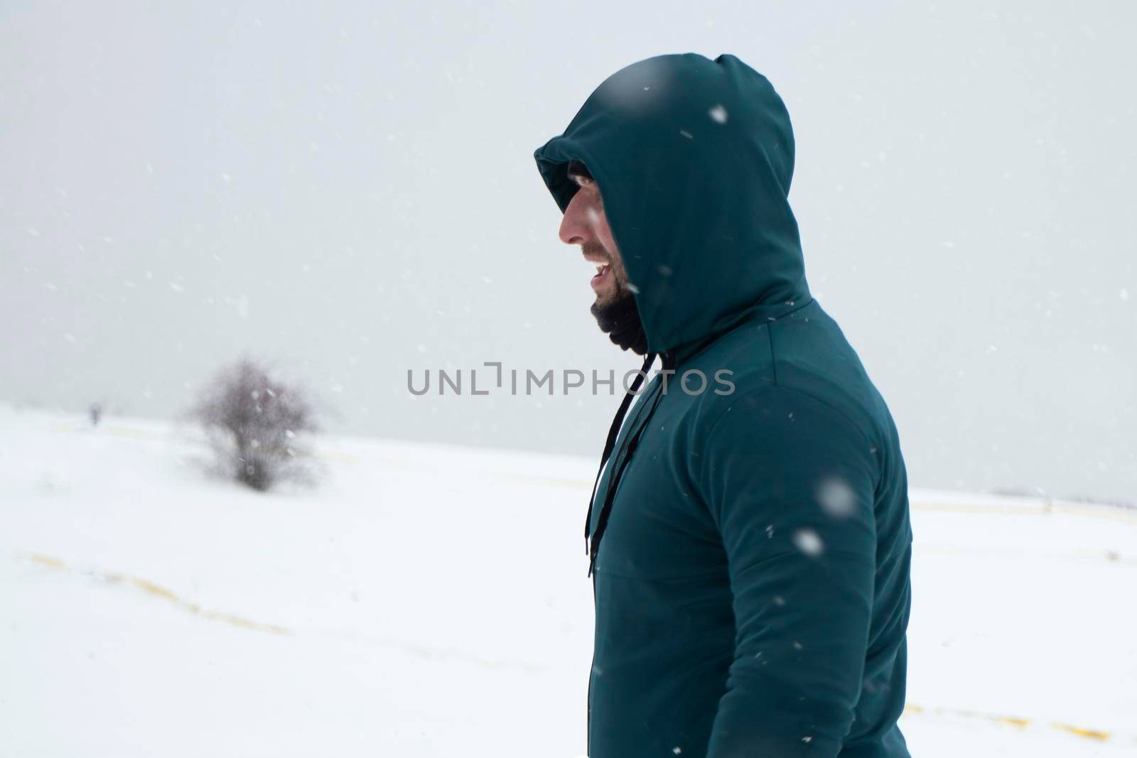 guy in green sports raglan on the background of the snowy horizon. Snowfall. The concept of doing sports in snowy weather. High quality photo