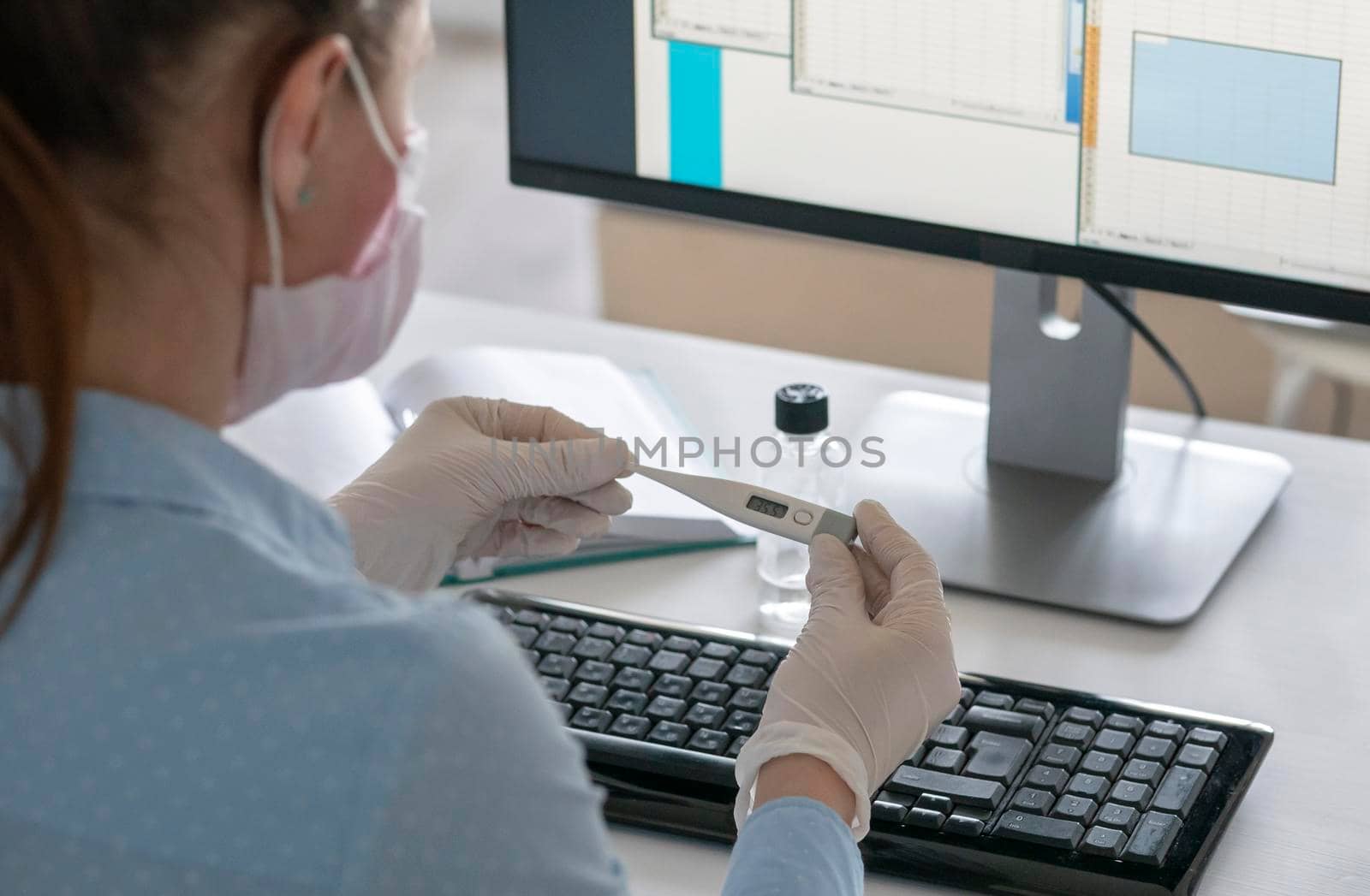 Unrecognizable sick woman holding smartphone and thermometer in hands, working on a laptop home quarantine isolation Covid-19 pandemic Corona virus. by Jyliana