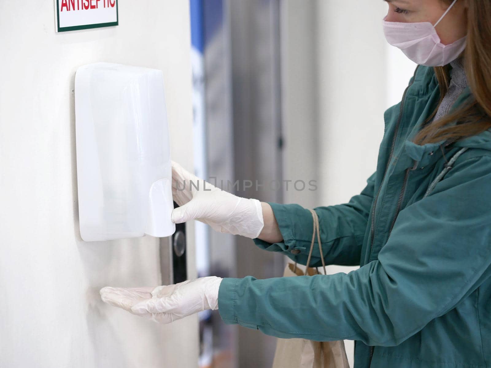 Hands using automatic sanitizer dispenser at supermarket. Disinfectant in a shopping mall during the coronavirus epidemic. by Jyliana