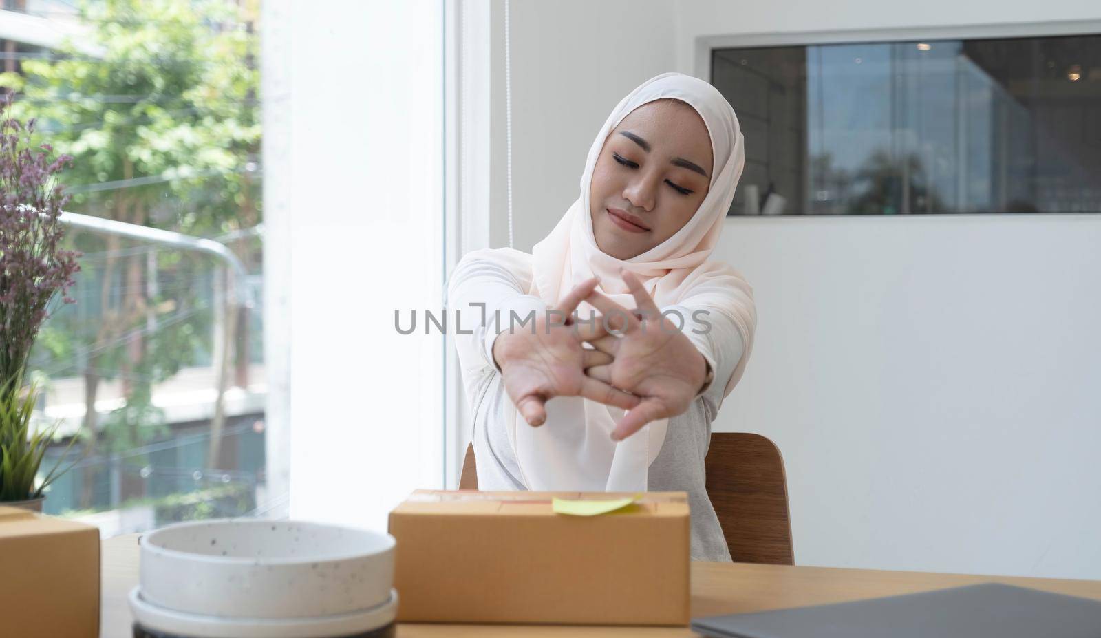 Beautiful Asian woman wearing a white Muslim dress. Stretching arms after successful online sales by wichayada