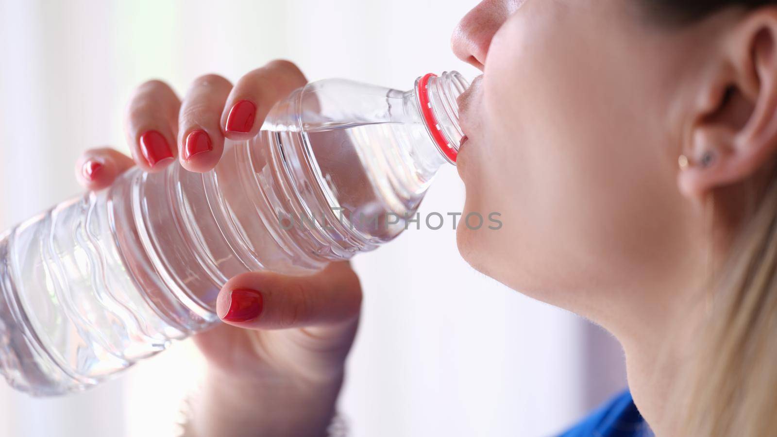 Woman drinking water from plastic bottle closeup by kuprevich