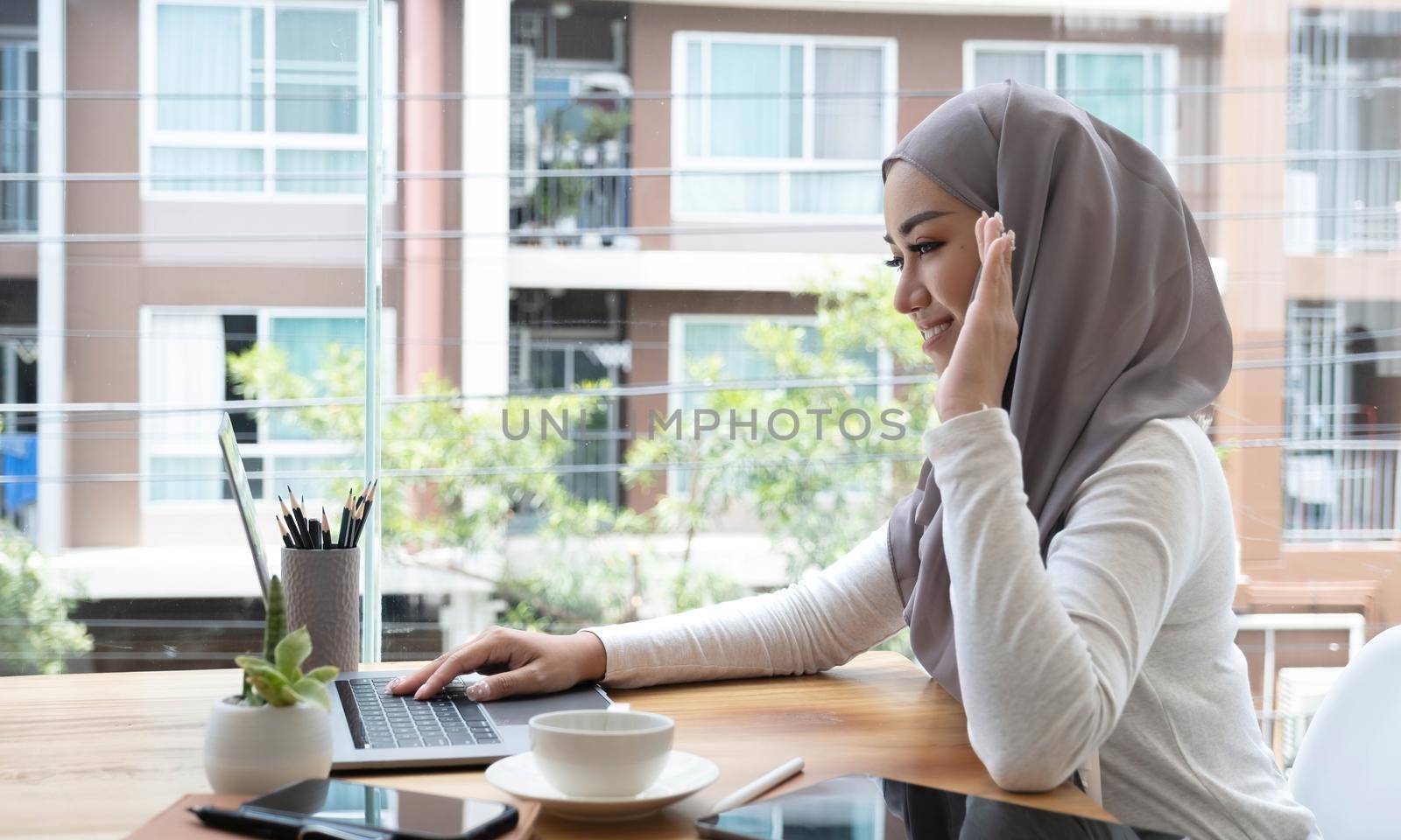 Beautiful gorgeous muslim woman or businesswoman having an online meeting via laptop computer at her office. by wichayada