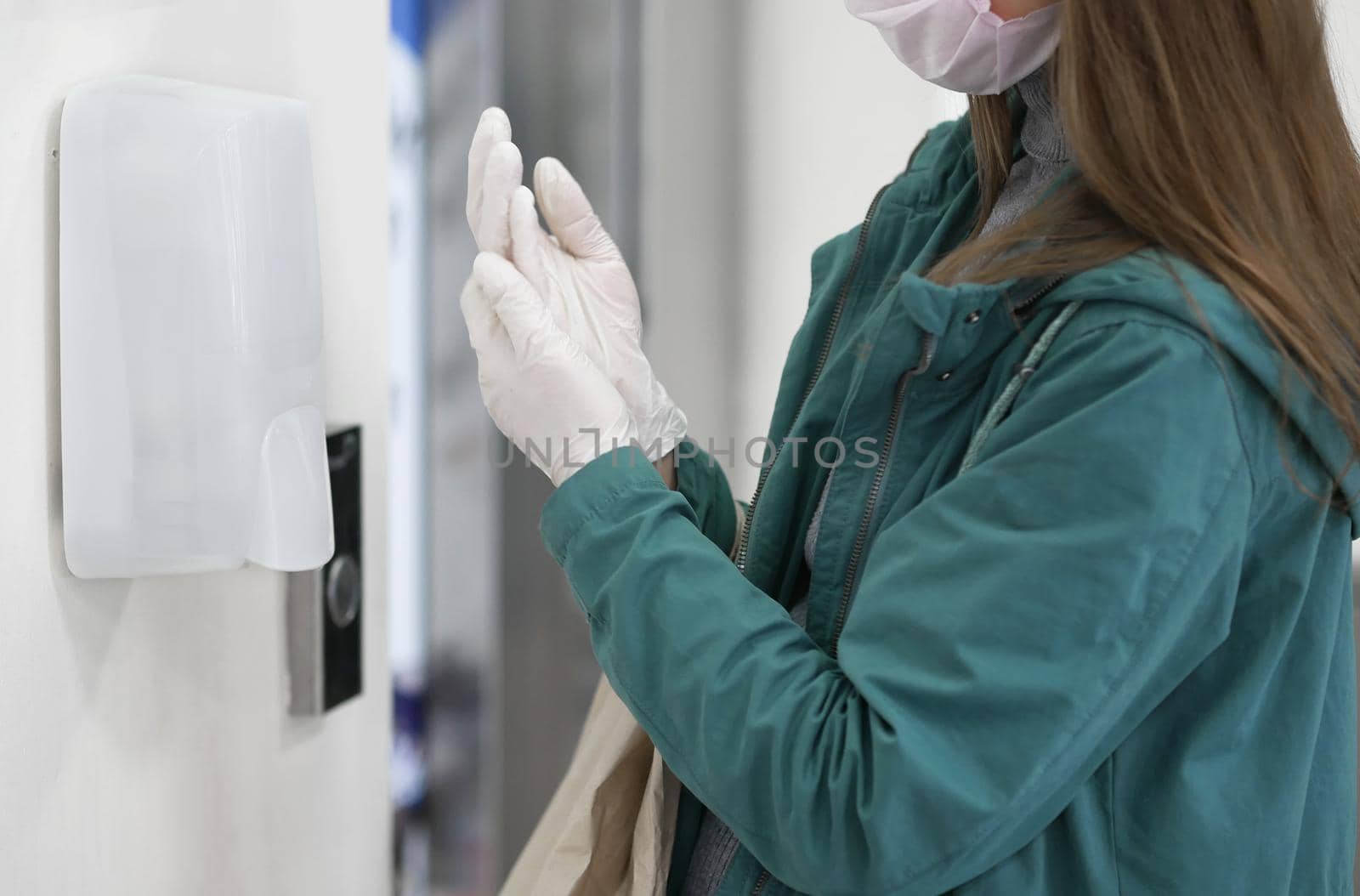 Hands using automatic sanitizer dispenser at supermarket. Disinfectant in a shopping mall during the coronavirus epidemic. by Jyliana