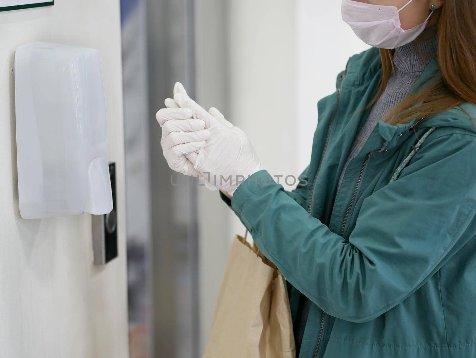 Washing hands in gloves using automatic sanitizer dispenser. Automatic sanitizer dispenser at supermarket. Coronavirus prevention. Coronavirus. Disinfectant in a shopping mall during the coronavirus epidemic.