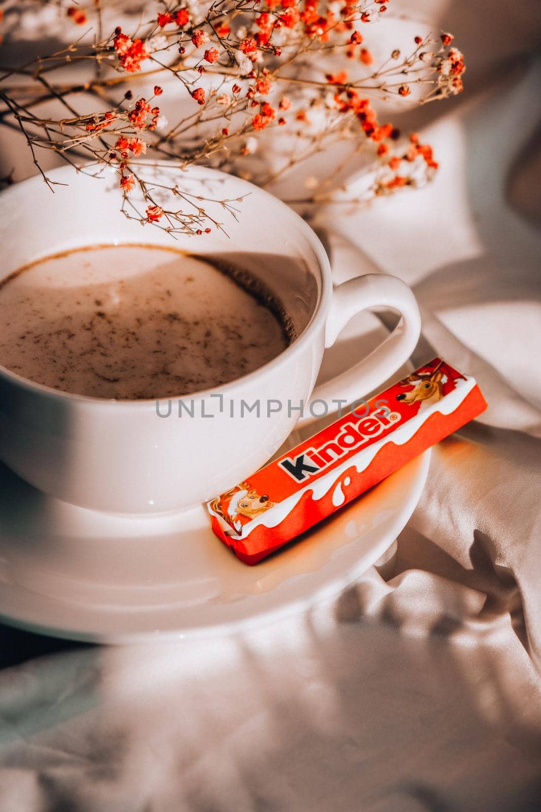 Kiev, Ukraine - 21 January 2021 White cup of milk and KINDER chocolate. Morning aesthetics vibes. Breakfast. Pink gypsophila flowers by anna_stasiia