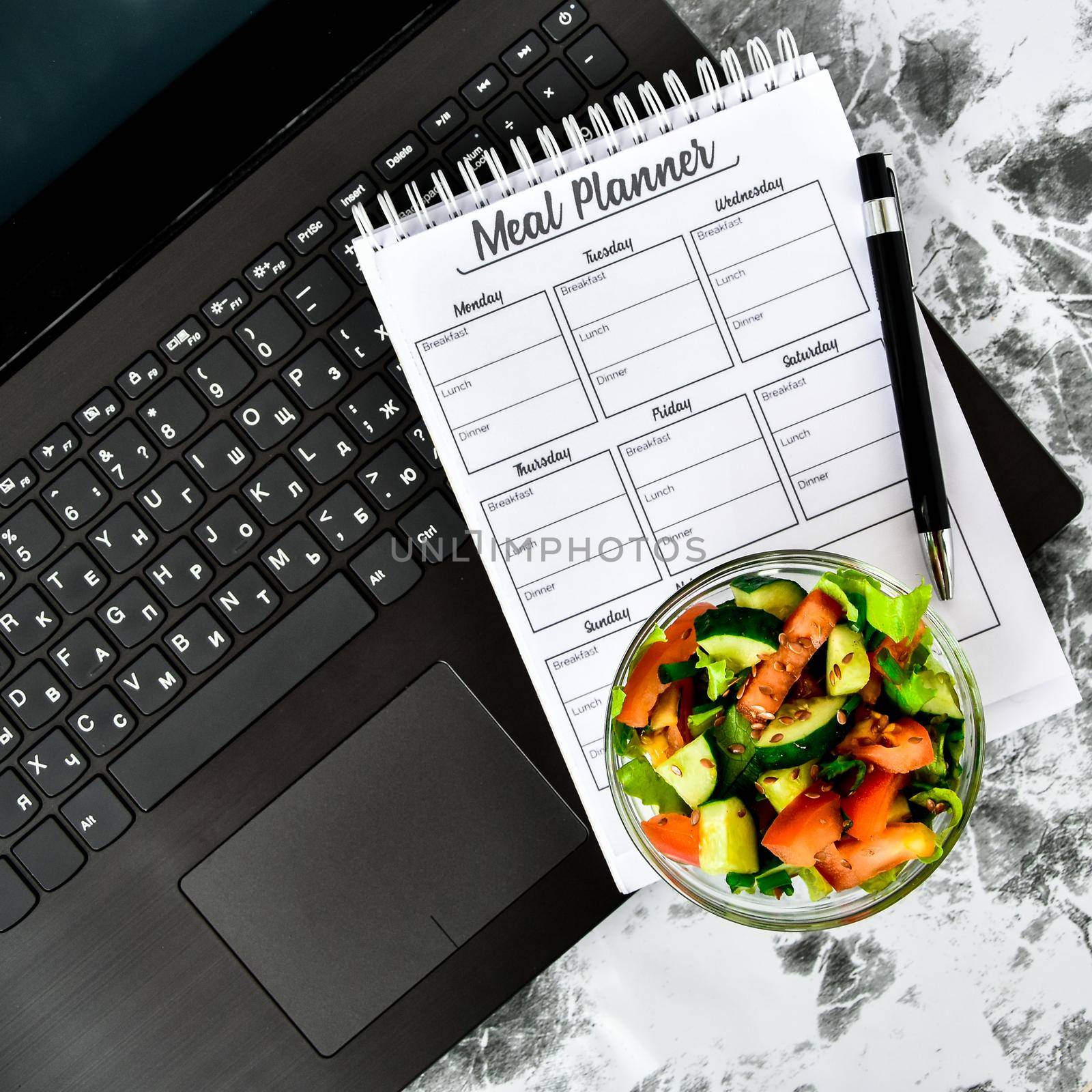 A meal plan for a week. Bowl with vegetable salad in the workplace near the computer. Lunch in the office during a break between work by anna_stasiia