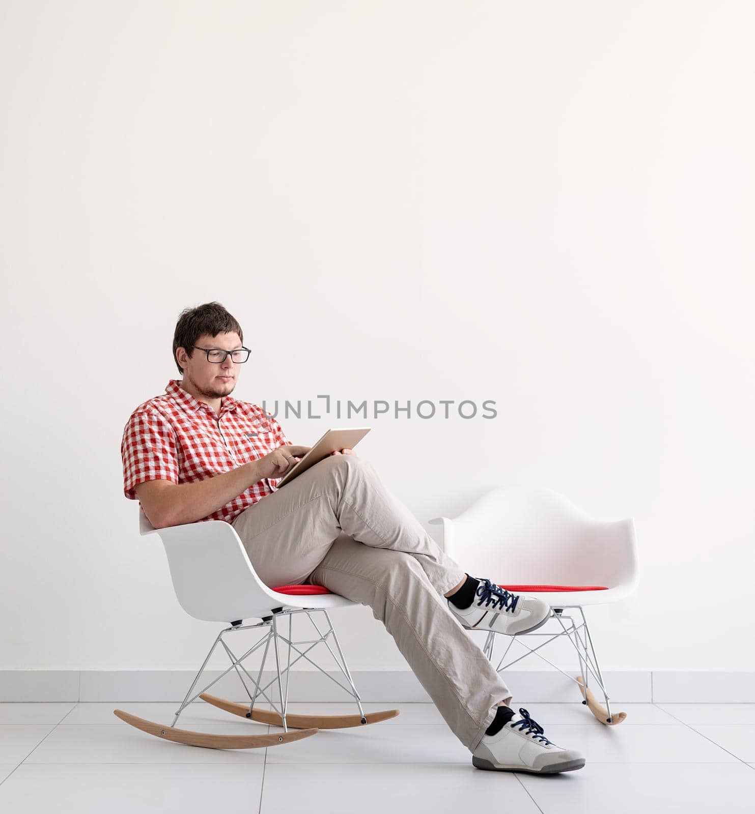 Online shopping concept. Young man sitting in the chair and shopping online using tablet , copy space