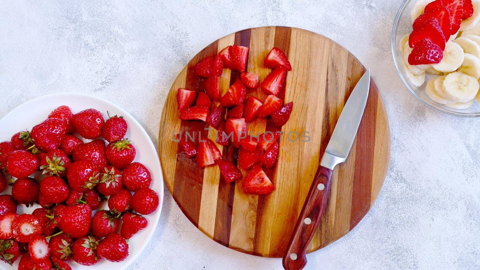 Sliced strawberry on wooden board. Preparing smoothie or milkshake with strawberry and banana. Top view. Flat lay