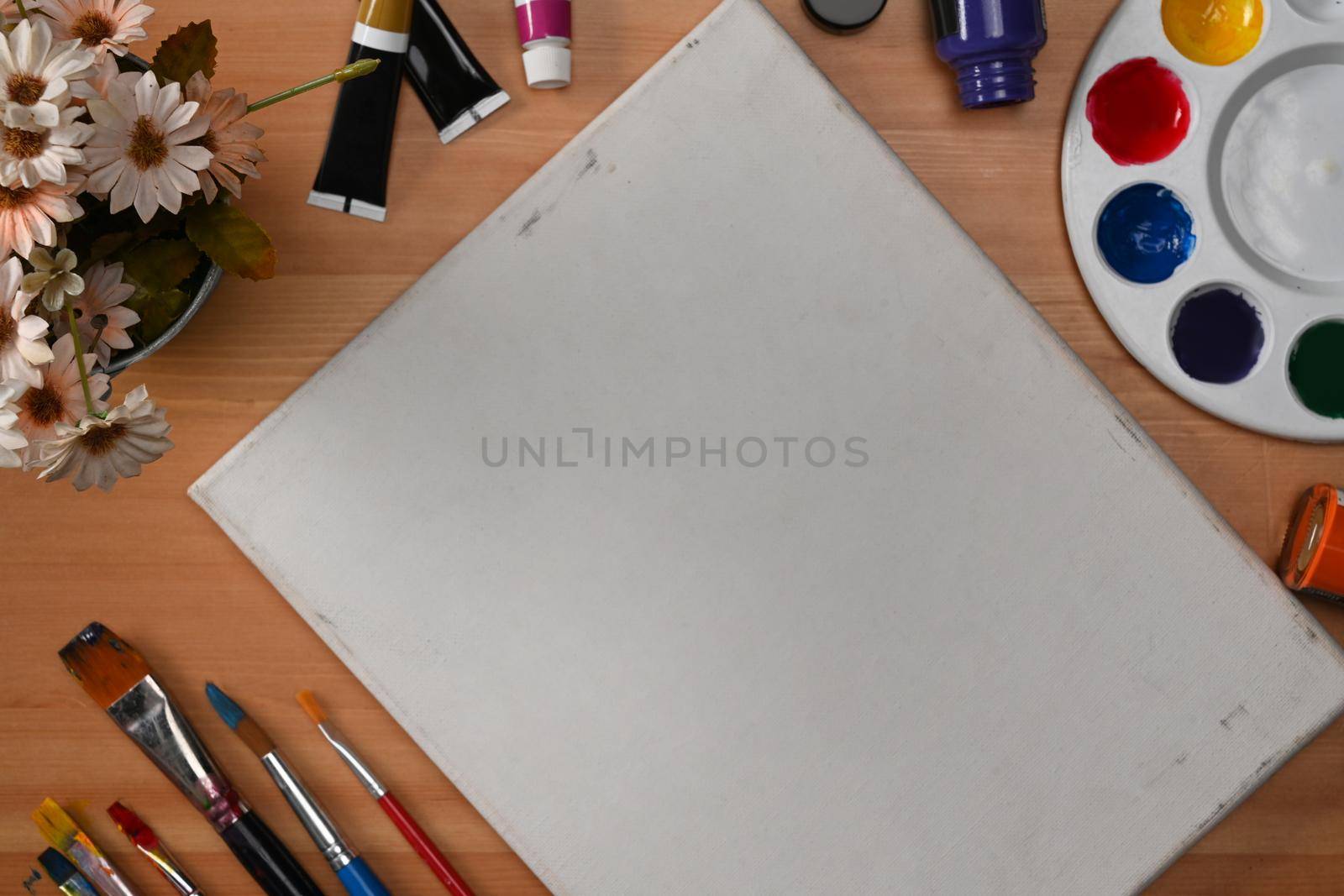 Top view blank canvas, watercolor and paintbrushes on wooden table. Professional painter workplace.