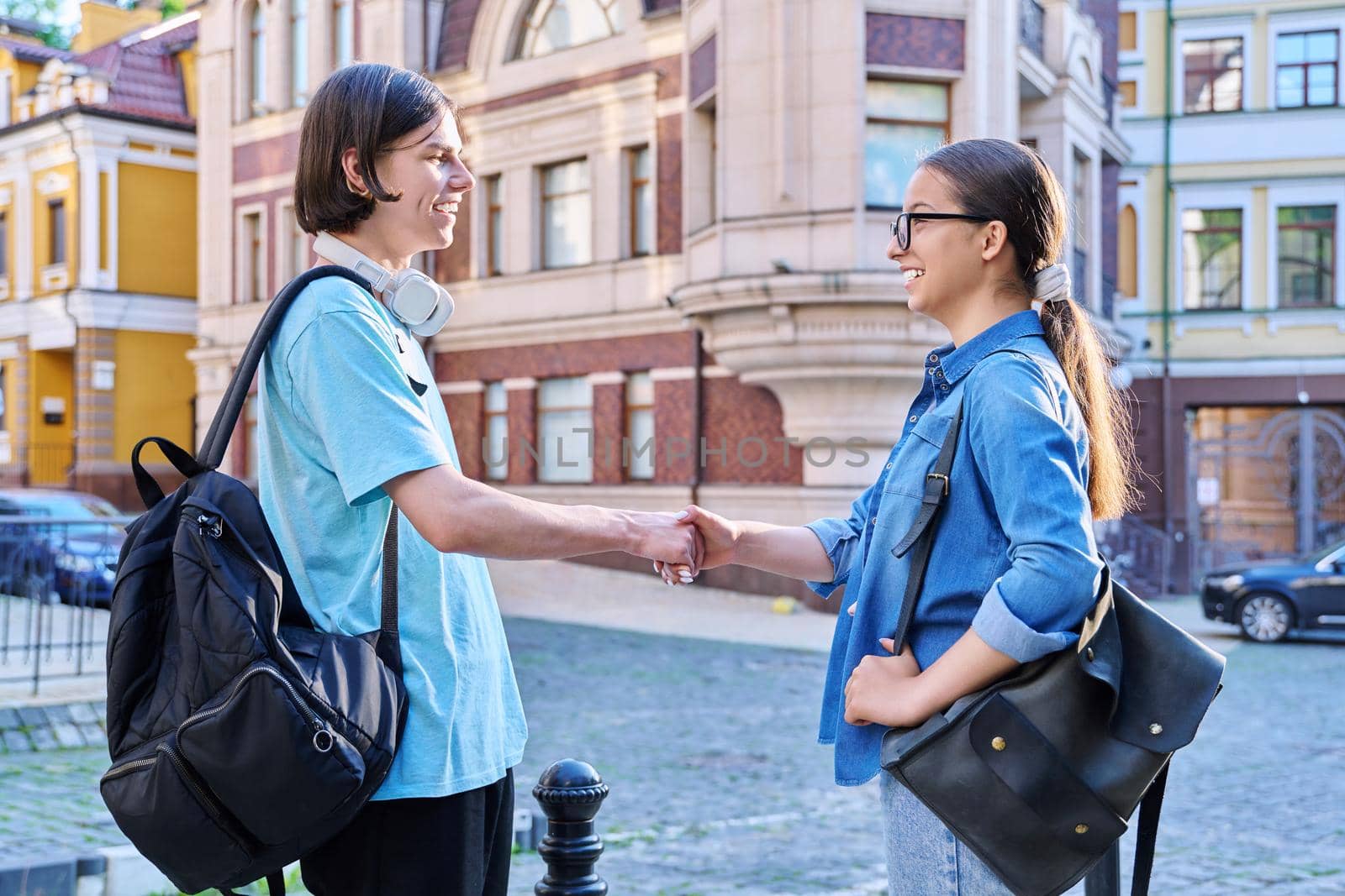 Teenage friends male and female talking on street of city. Fashionable having fun teenagers guy and girl together outdoor. Friendship, communication, holidays, lifestyle, youth, urban style