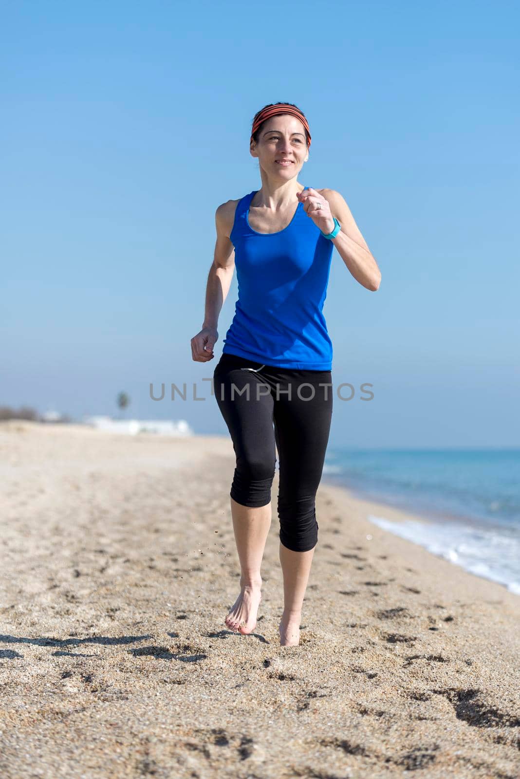 Front view of women jogging on beach close to water by raferto1973