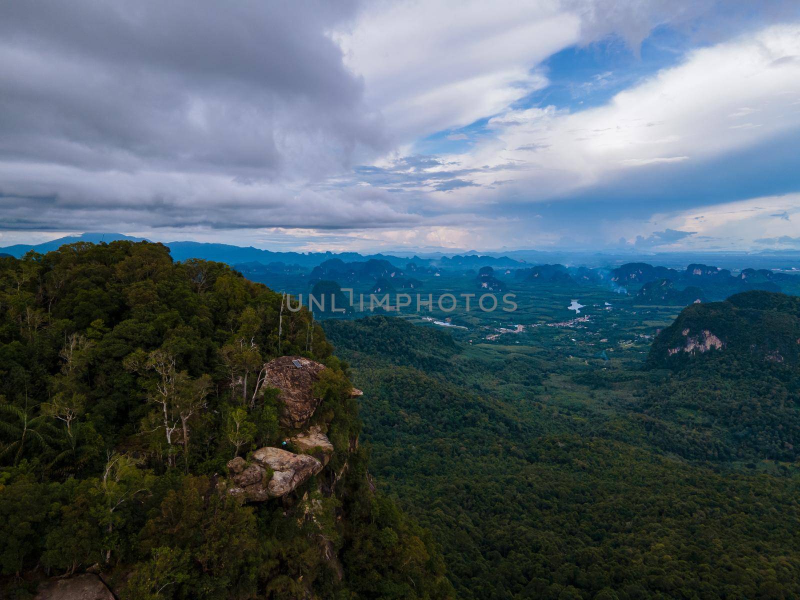 Dragon Crest mountain Krabi Thailand, a Young traveler sits on a rock that overhangs the abyss, with a beautiful landscape. Dragon Crest or Khuan Sai at Khao Ngon Nak Nature Trail in Krabi, Thailand