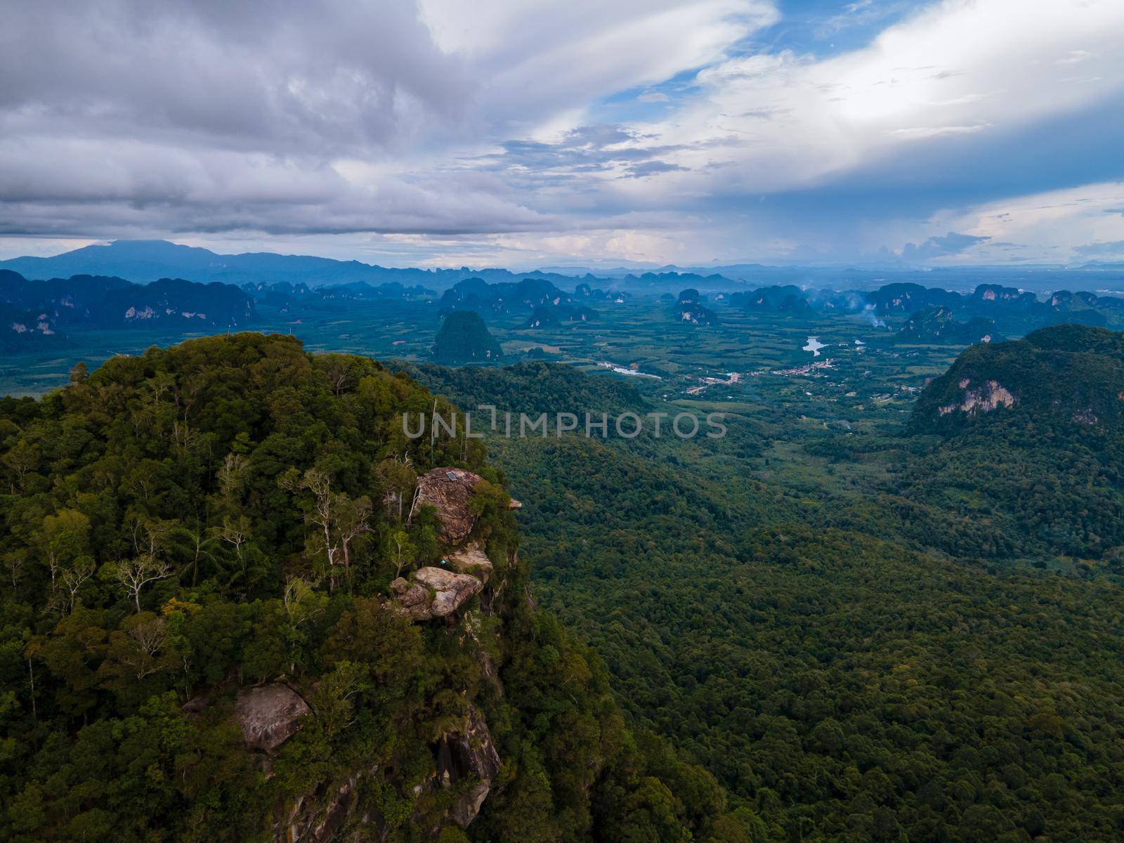 Dragon Crest mountain Krabi Thailand, a Young traveler sits on a rock that overhangs the abyss, with a beautiful landscape. Dragon Crest or Khuan Sai at Khao Ngon Nak Nature Trail in Krabi, Thailand