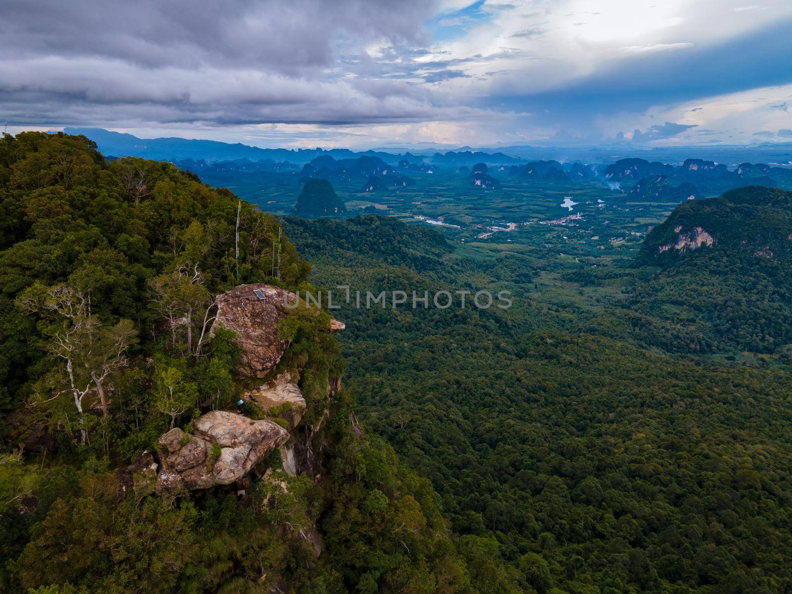 Dragon Crest mountain Krabi Thailand, a Young traveler sits on a rock that overhangs the abyss, with a beautiful landscape. Dragon Crest or Khuan Sai at Khao Ngon Nak Nature Trail in Krabi, Thailand