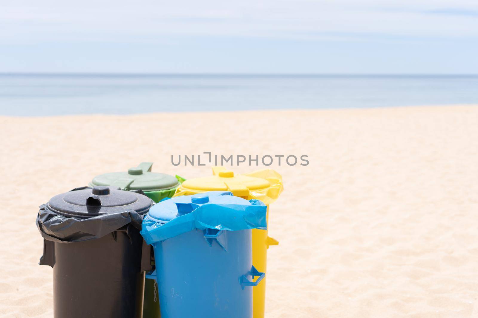 Clean beach garbage bins. Multi colored garbage containers for separate collection of garbage stand on empty beaches near the ocean