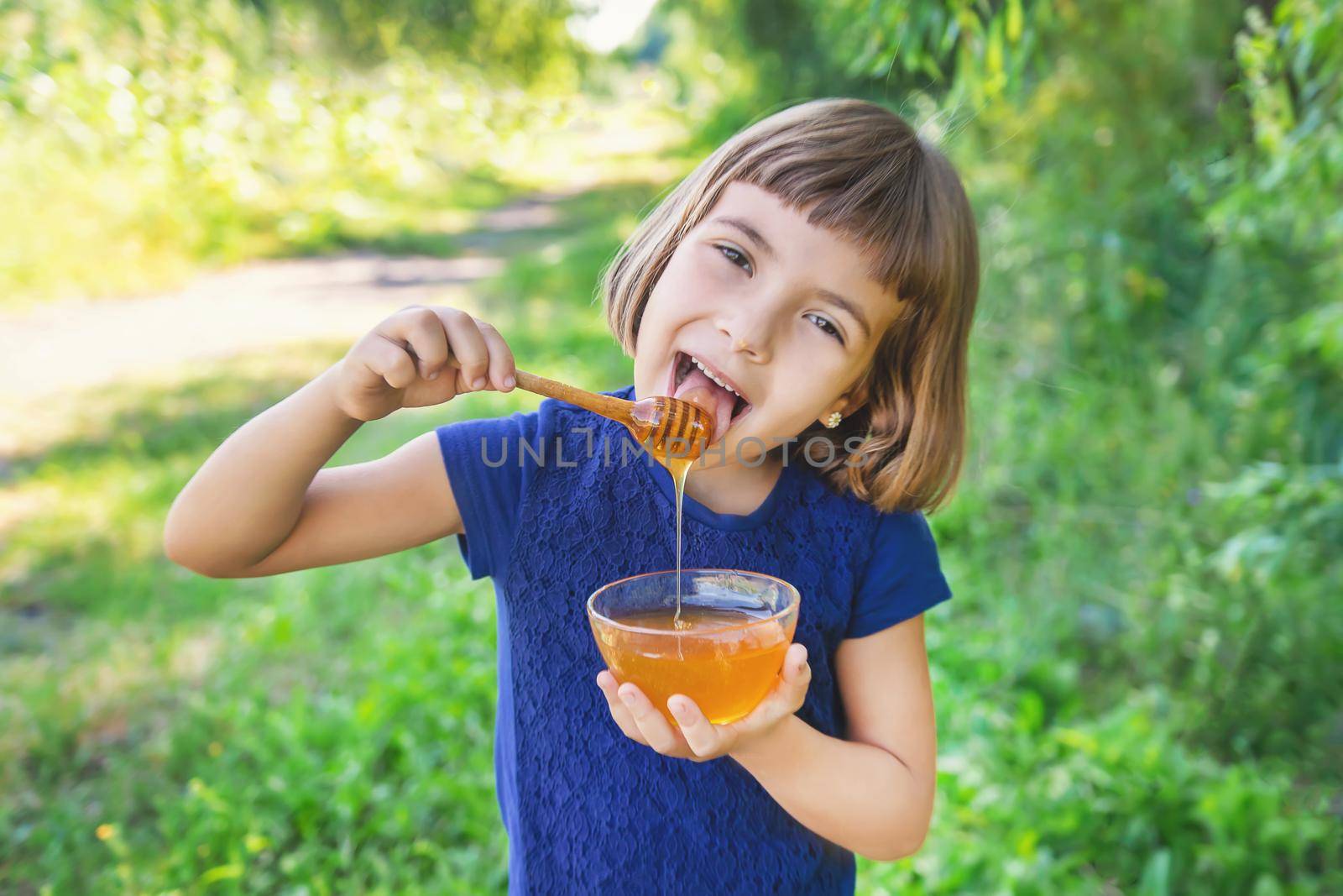 Child a plate of honey in the hands. Selective focus.