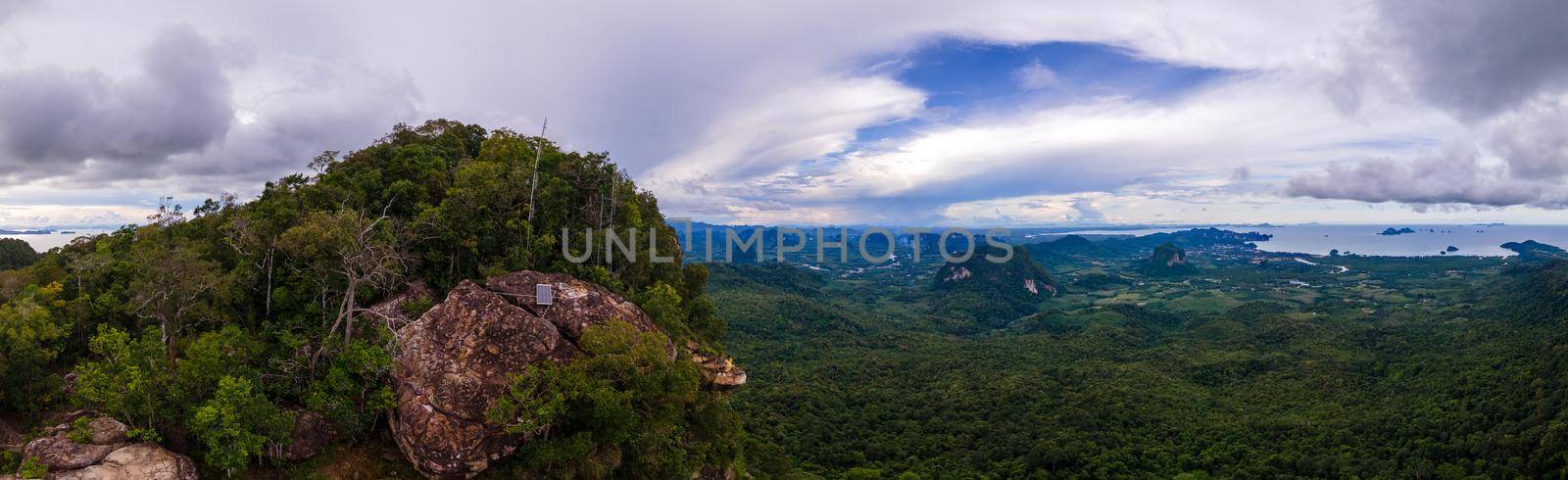 Dragon Crest mountain Krabi Thailand, a Young traveler sits on a rock that overhangs the abyss, with a beautiful landscape. Dragon Crest or Khuan Sai at Khao Ngon Nak Nature Trail by fokkebok