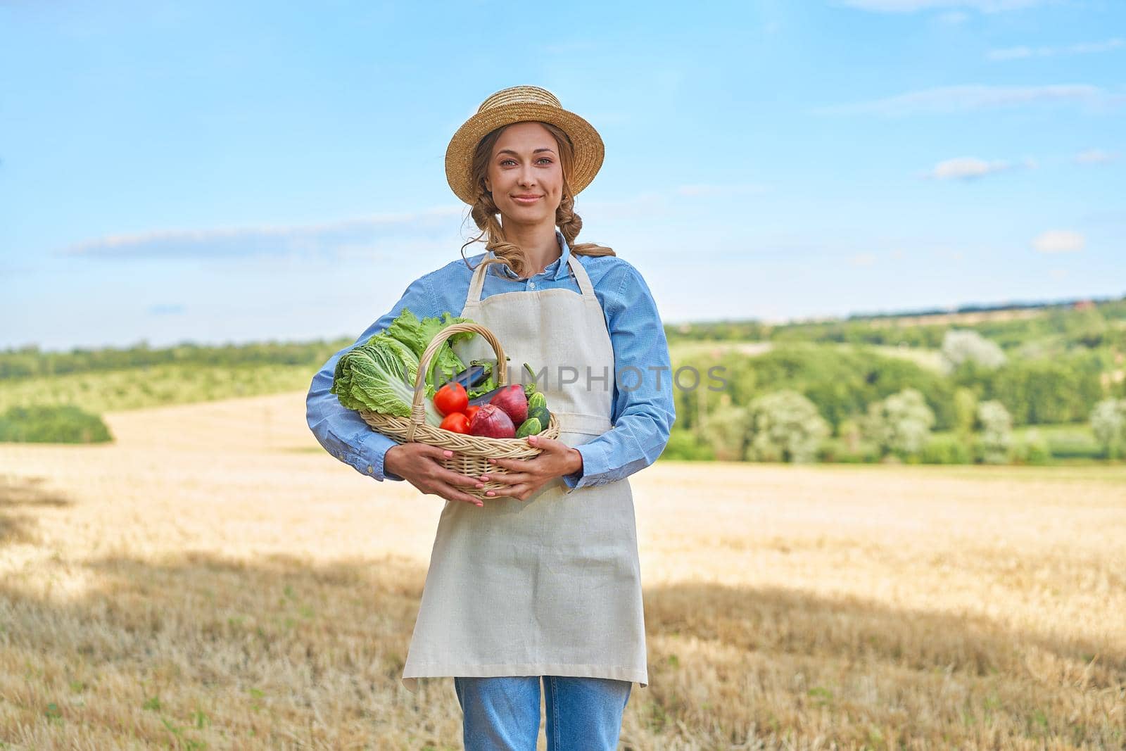 Woman farmer straw hat holding basket vegetable onion tomato salad cucumber standing farmland smiling Female agronomist specialist farming agribusiness Happy Girl dressed apron cultivated wheat field