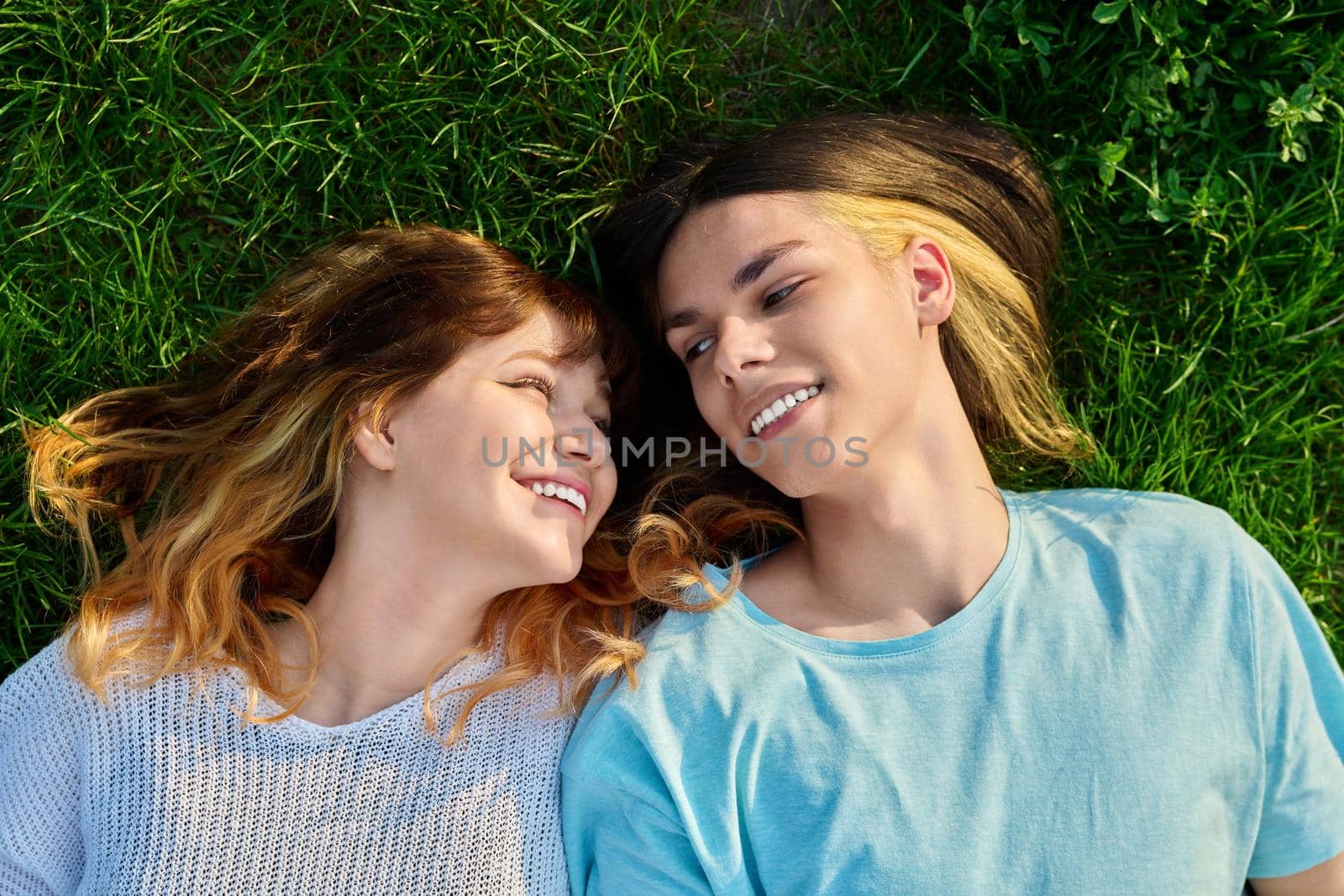 Couple of teenagers friends on green grass background by VH-studio