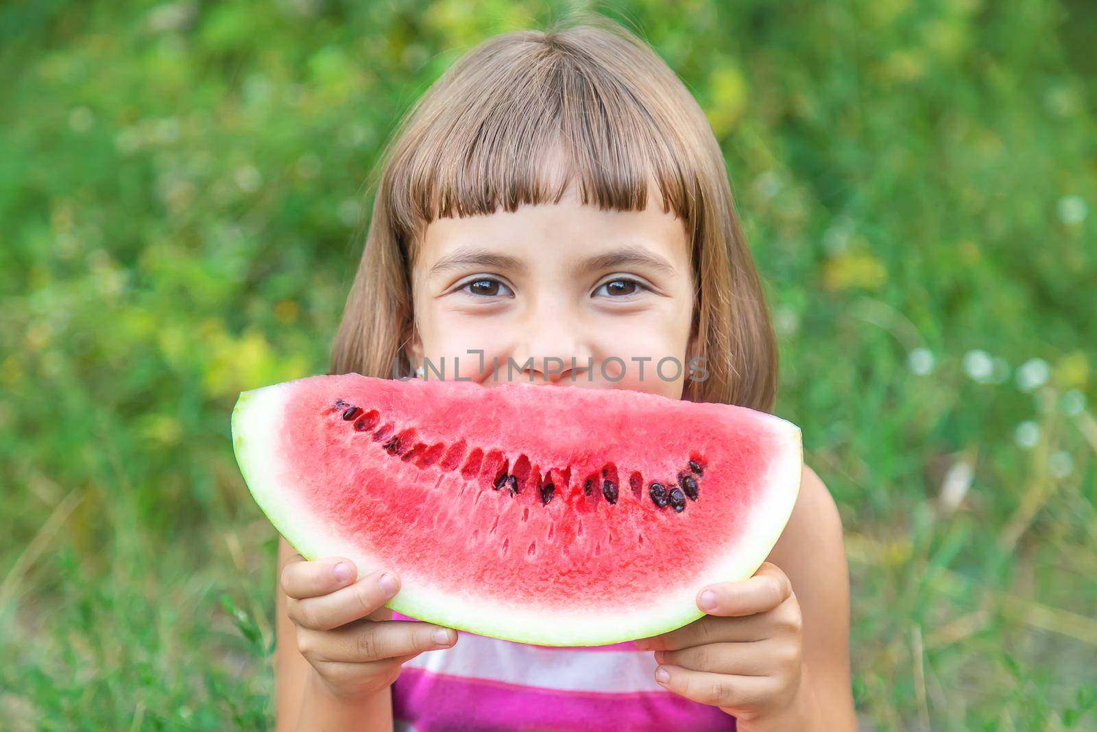 child eats a watermelon in the garden. Selective focus. by yanadjana