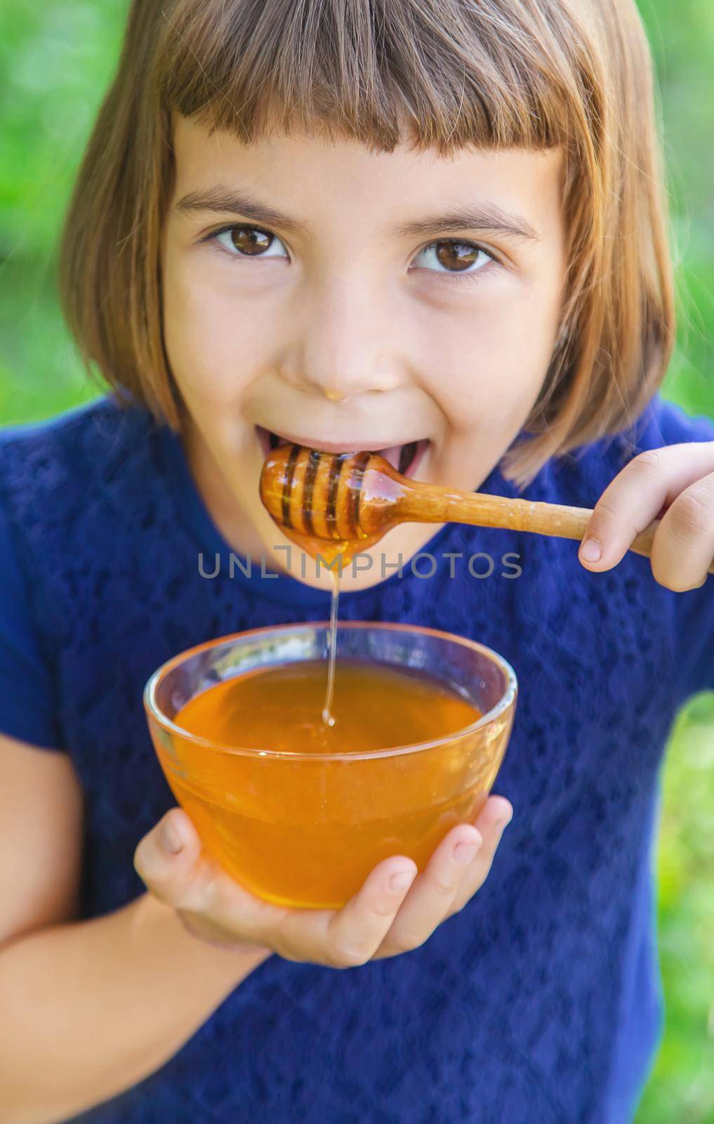 Child a plate of honey in the hands. Selective focus. by yanadjana