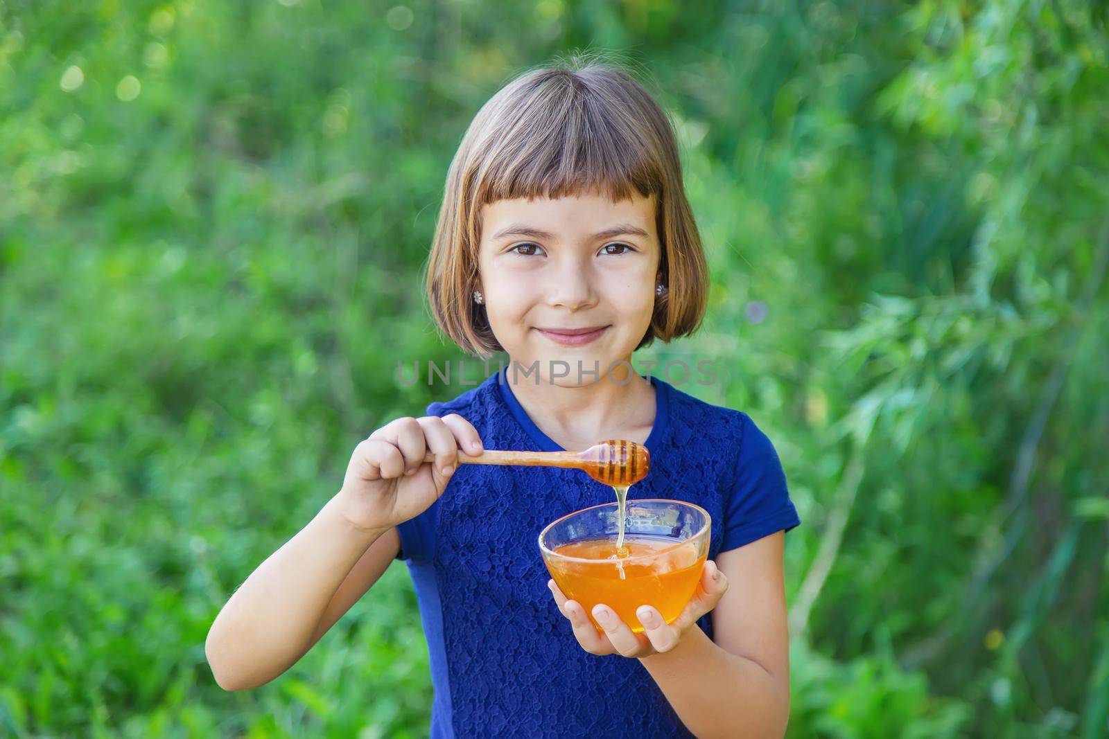 Child a plate of honey in the hands. Selective focus.