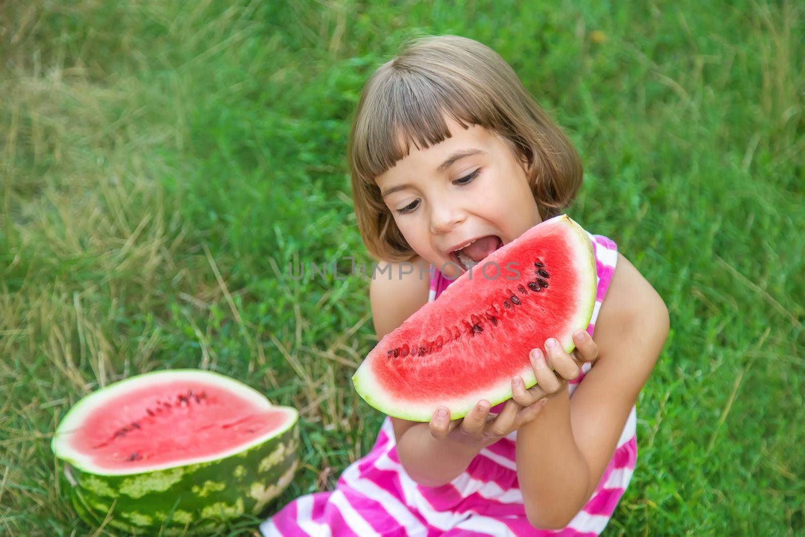 child eats a watermelon in the garden. Selective focus. by yanadjana