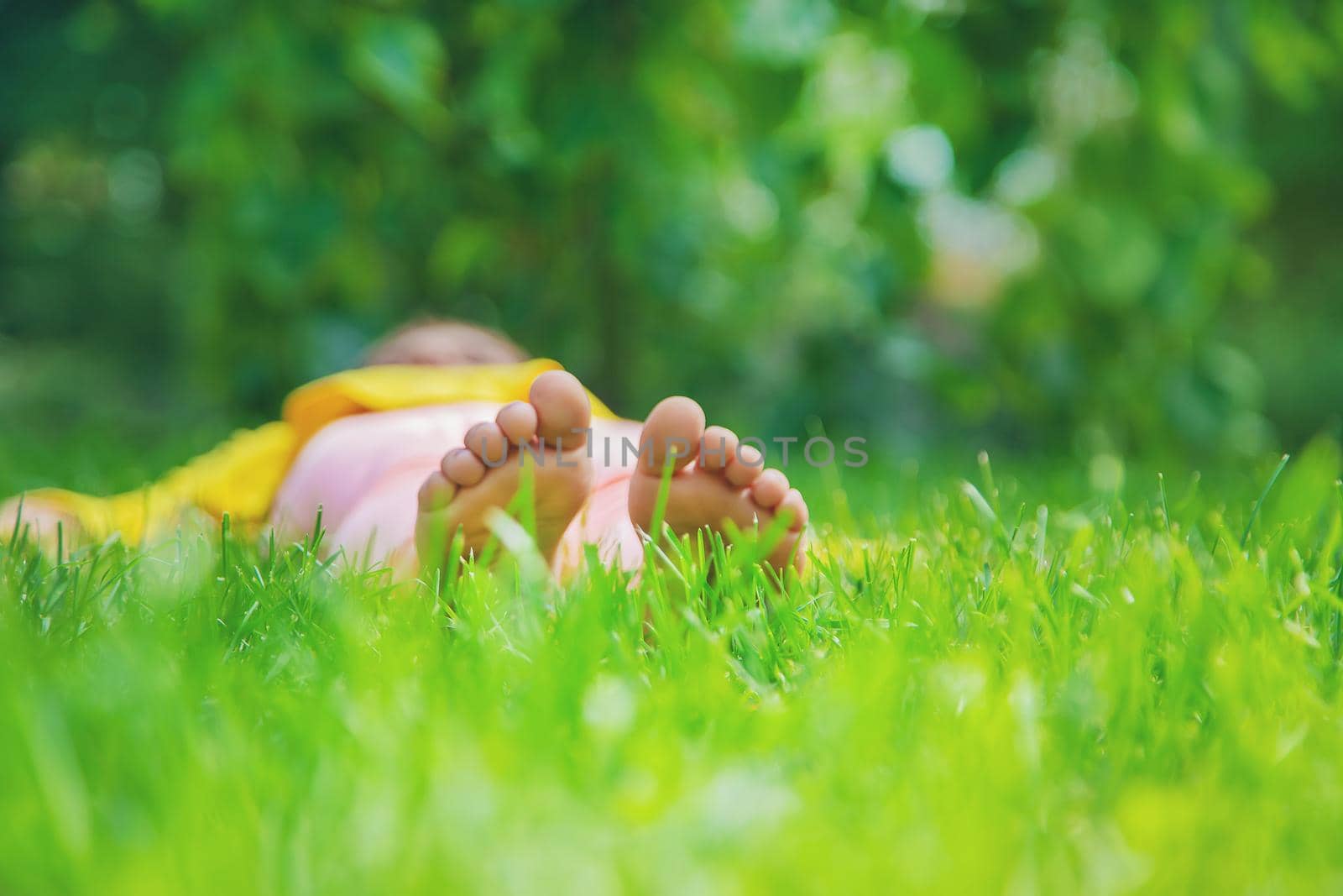 The child lies on the grass. Selective focus. by yanadjana