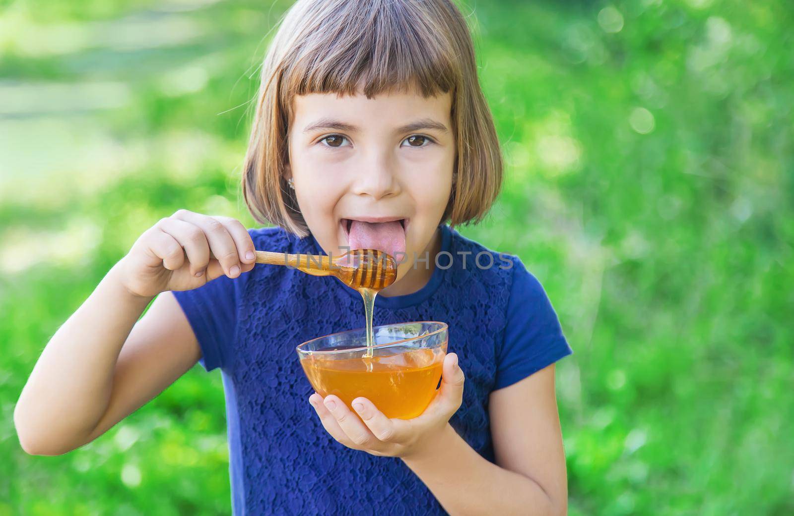 Child a plate of honey in the hands. Selective focus.