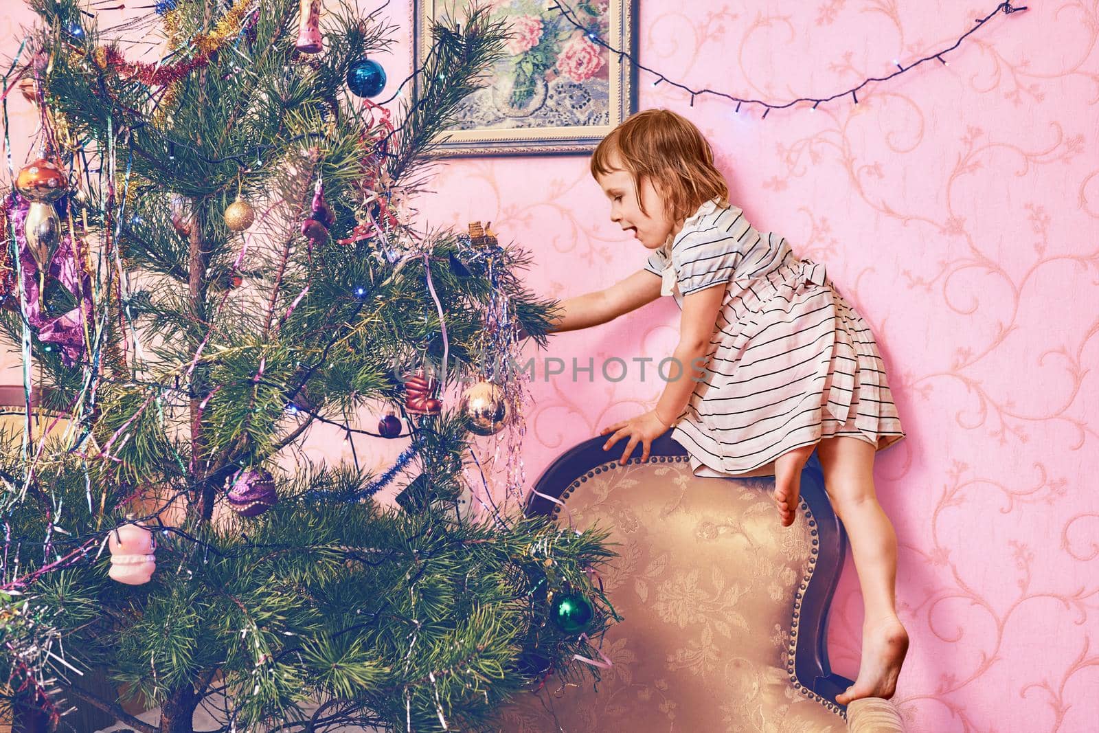 Happy little girl decorate christmas tree with toys by jovani68