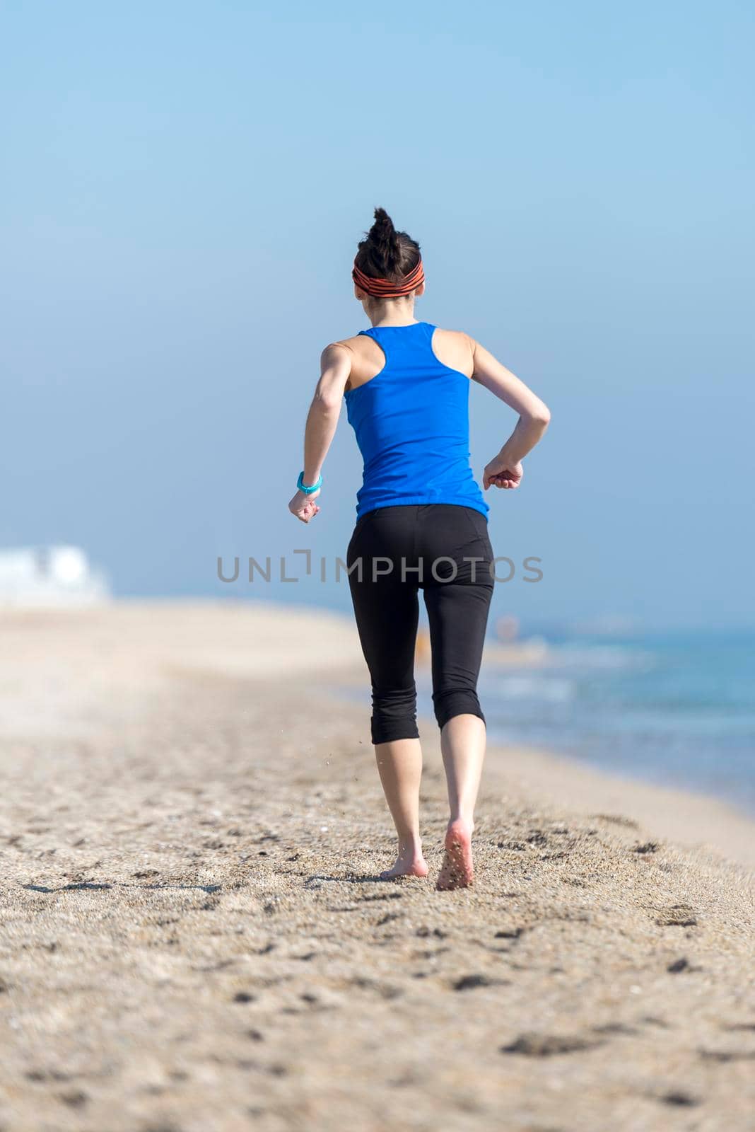 Rear view of women jogging on beach close to water by raferto1973