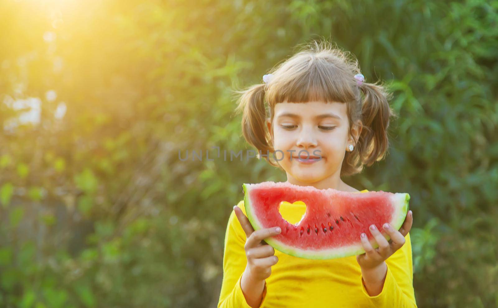 child eats a watermelon in the garden. Selective focus. by yanadjana