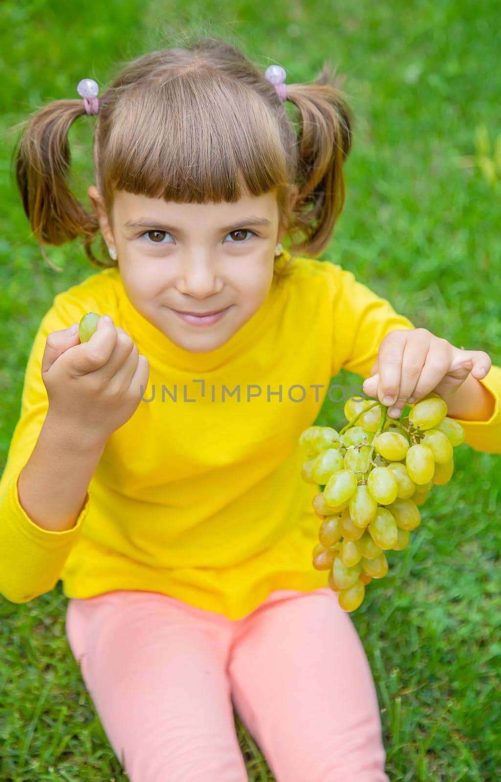 The child eats white grapes. Selective focus.