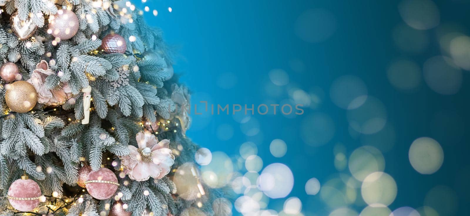 Magically decorated Christmas Tree with balls, ribbons and garlands on a blurred blue shiny, fairy and sparkling background