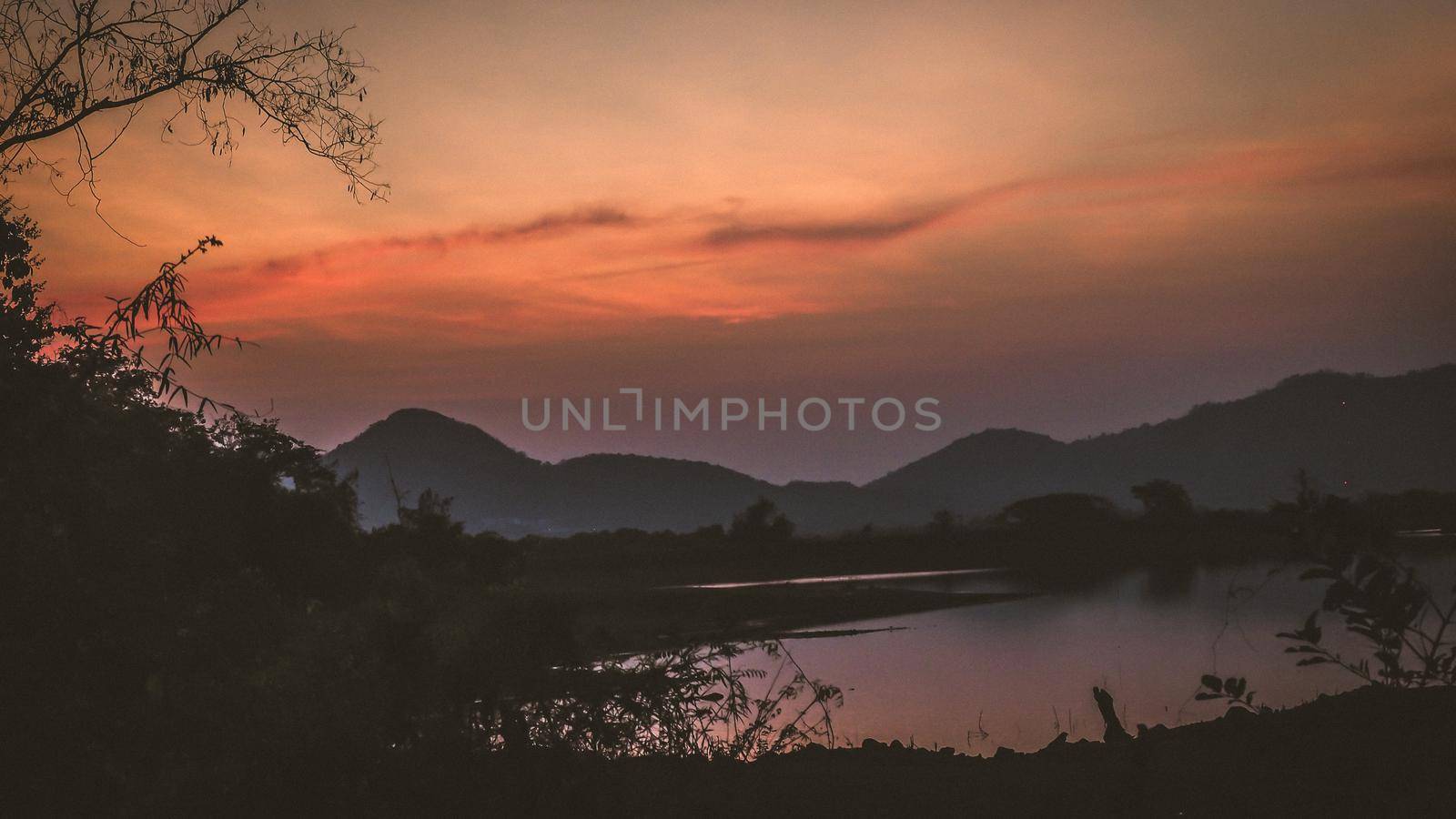 Landscape with orange and purple at sunset  silhouettes of mountains, hills and forest lake