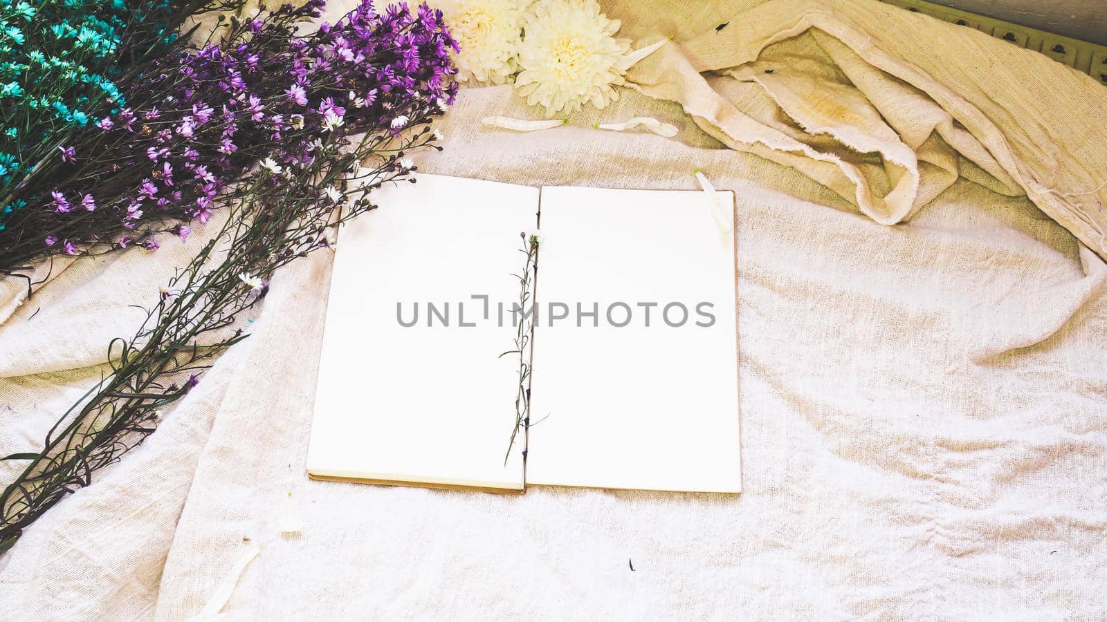 Blank white paper notebook and flower decoration. Greeting card on a white natural; linen background. Top view. Copy space. by Petrichor