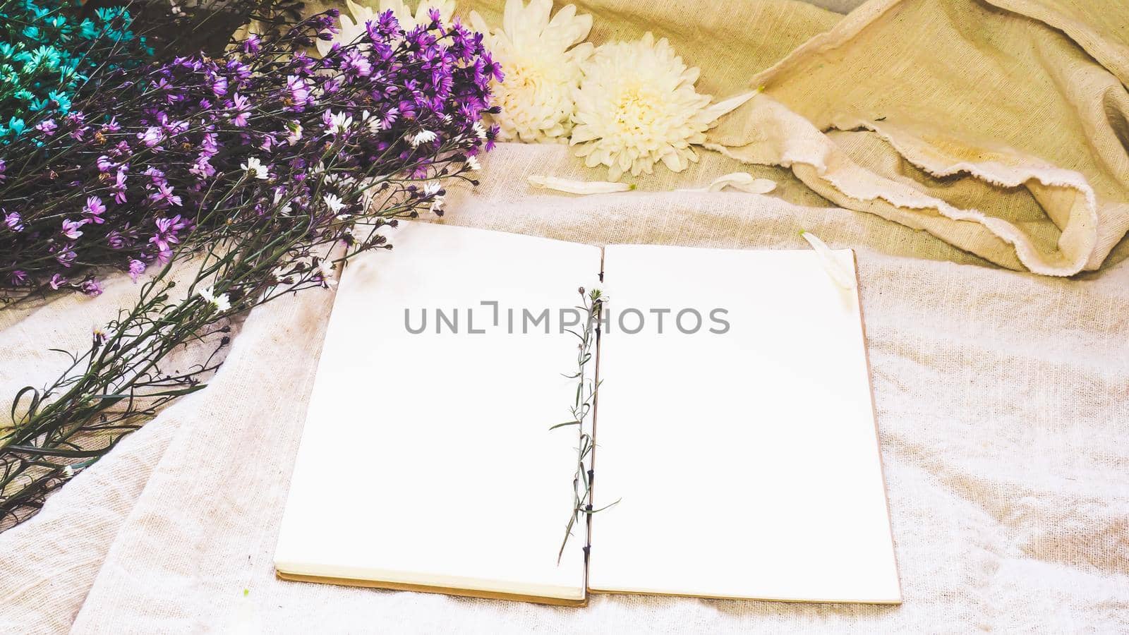 Blank white paper notebook and flower decoration. Greeting card on a white natural; linen background. Top view. Copy space. by Petrichor